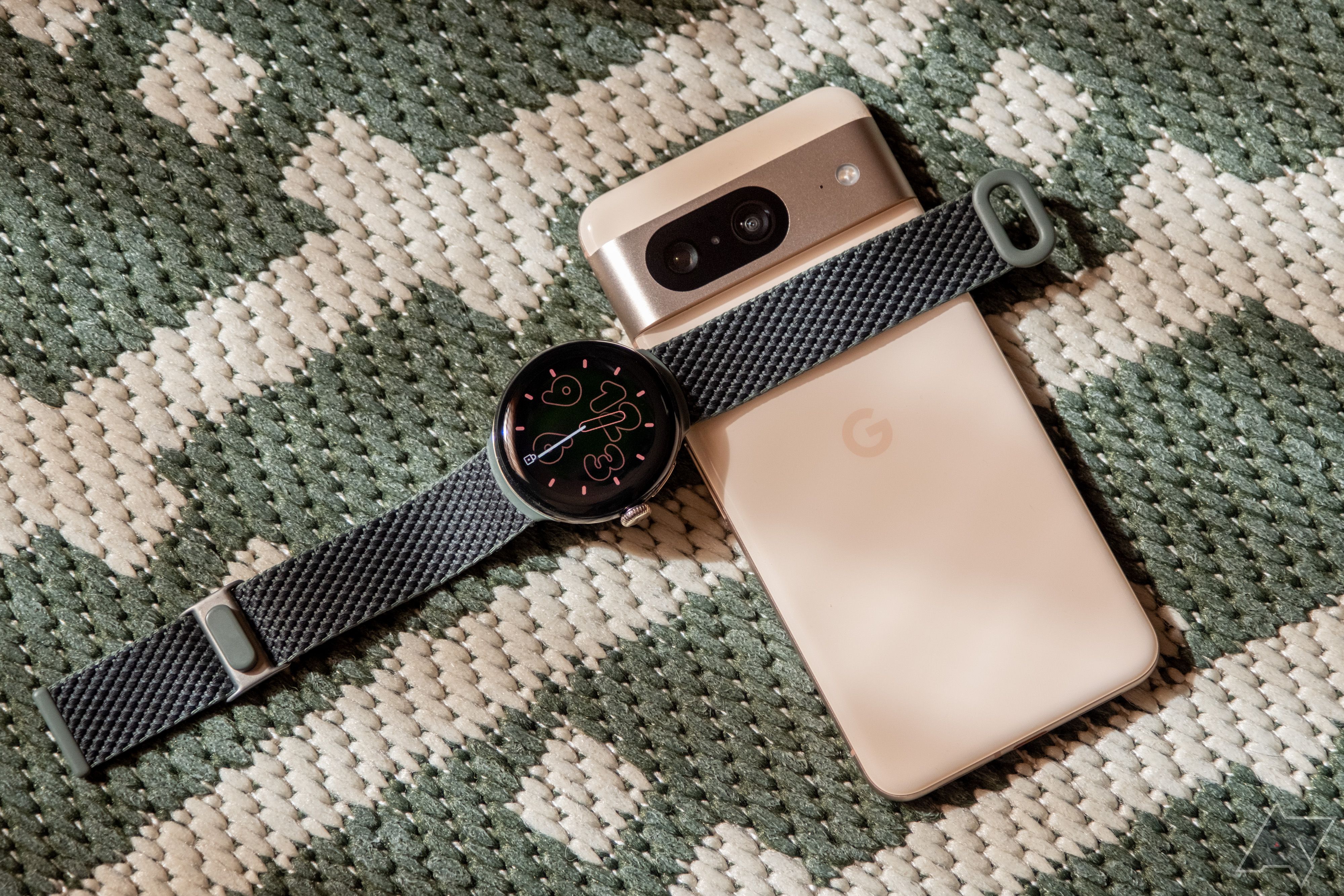 Um Google Pixel Watch 2 fica em cima de um smartphone Pixel 8