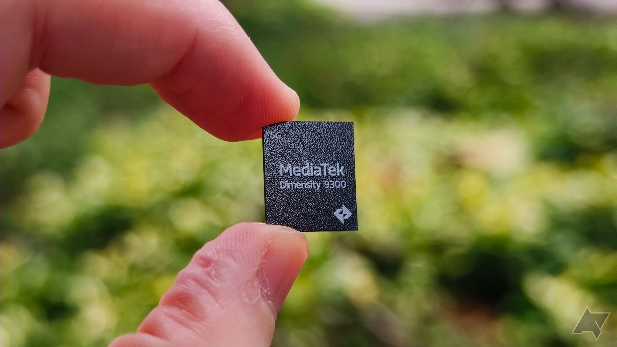 Lado do logotipo do chip MediaTek Dimensity 9300 em frente a um parque verde