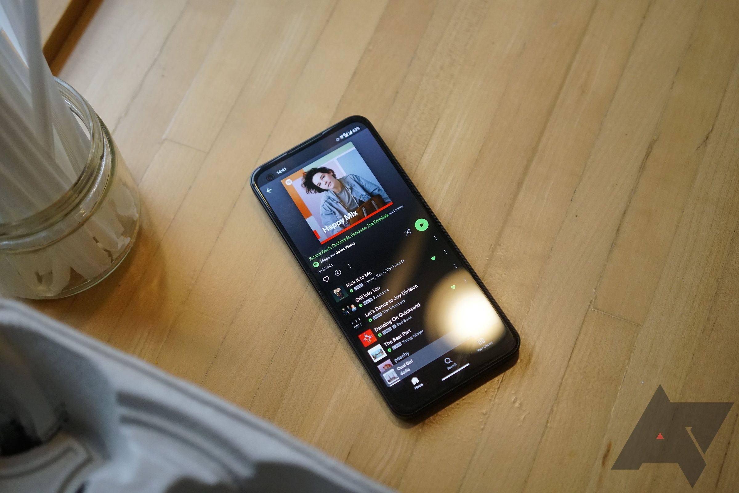 Um telefone com o aplicativo Spotify aberto para uma playlist está sobre uma mesa de madeira.