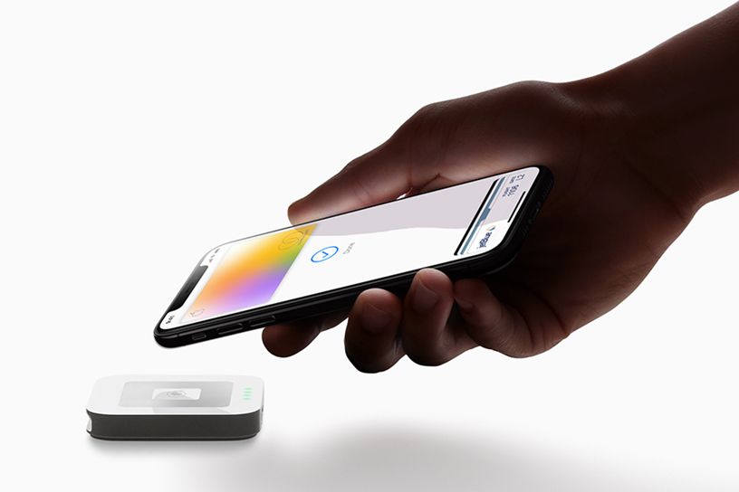 Uma mão usando o Apple Card no app Wallet para pagar em um sensor.