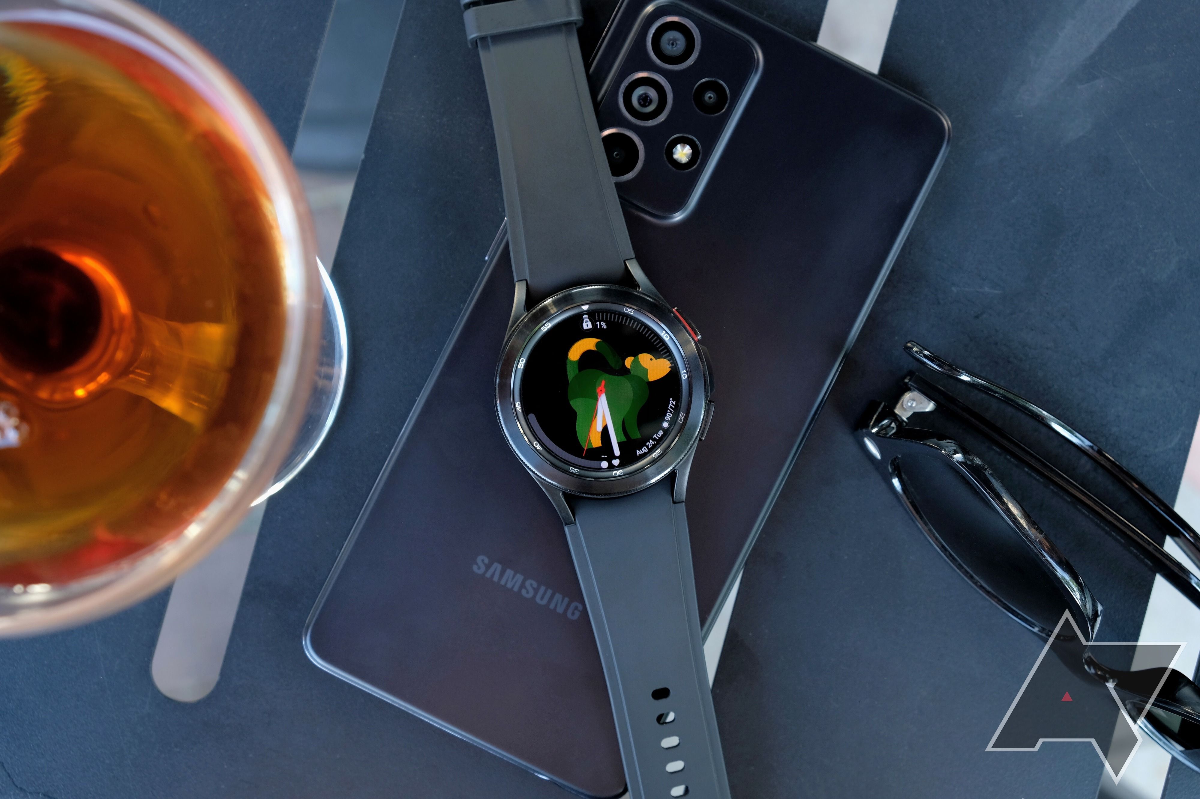 Um smartwatch colocado em cima de um smartphone Samsung virado para baixo