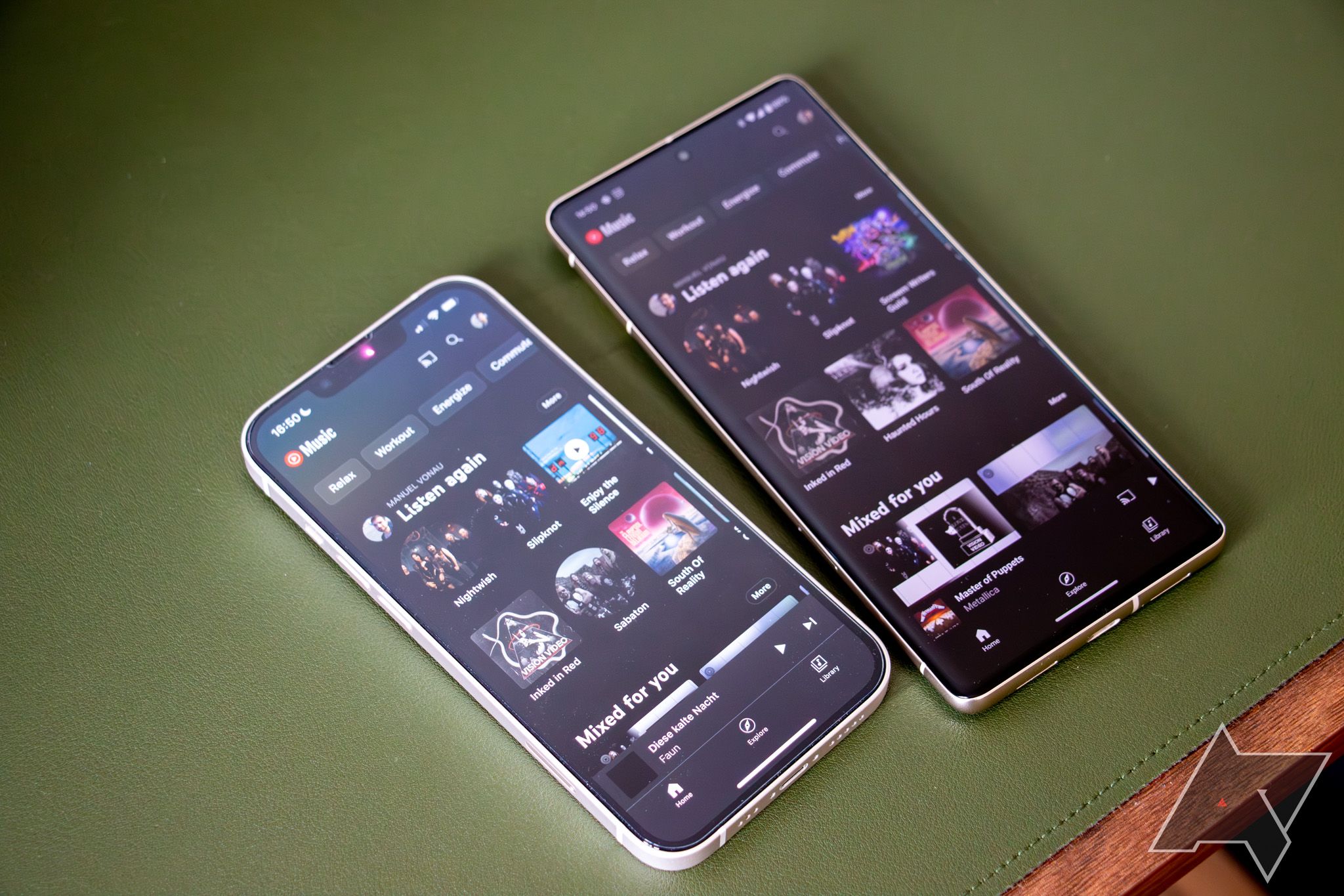 Um Apple iPhone 13 ao lado de um Google Pixel 7 Pro em uma superfície verde, com o app YouTube Music aberto em ambos