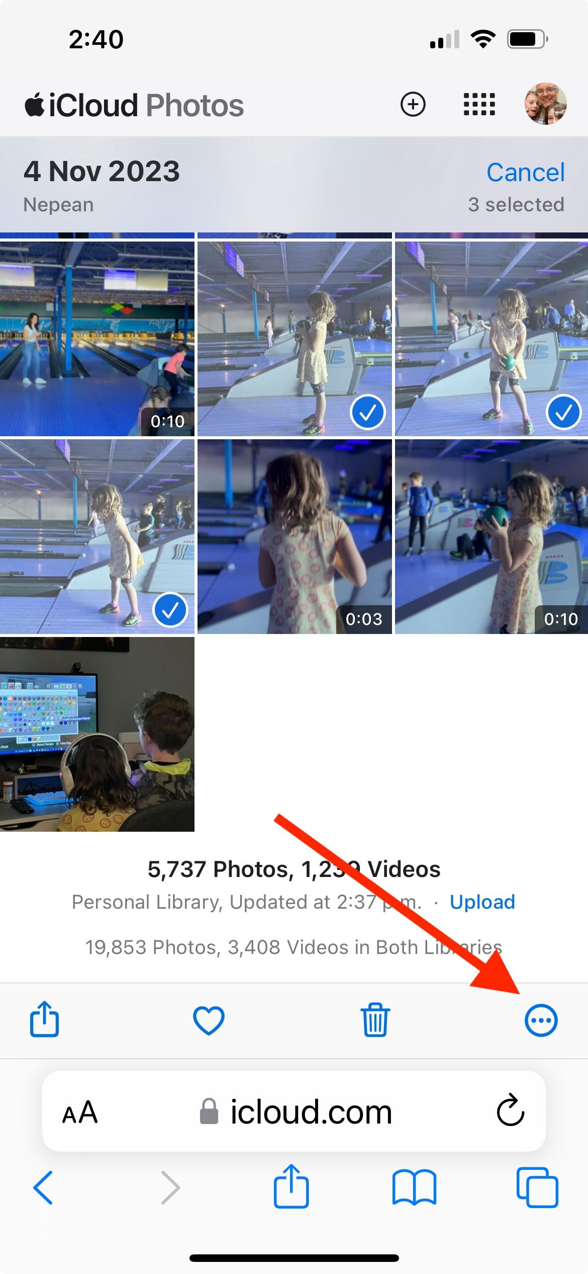Uma seta vermelha apontando para a opção mais no canto inferior direito do site iCloud Photos, com várias fotos mostrando marcas de seleção azuis.