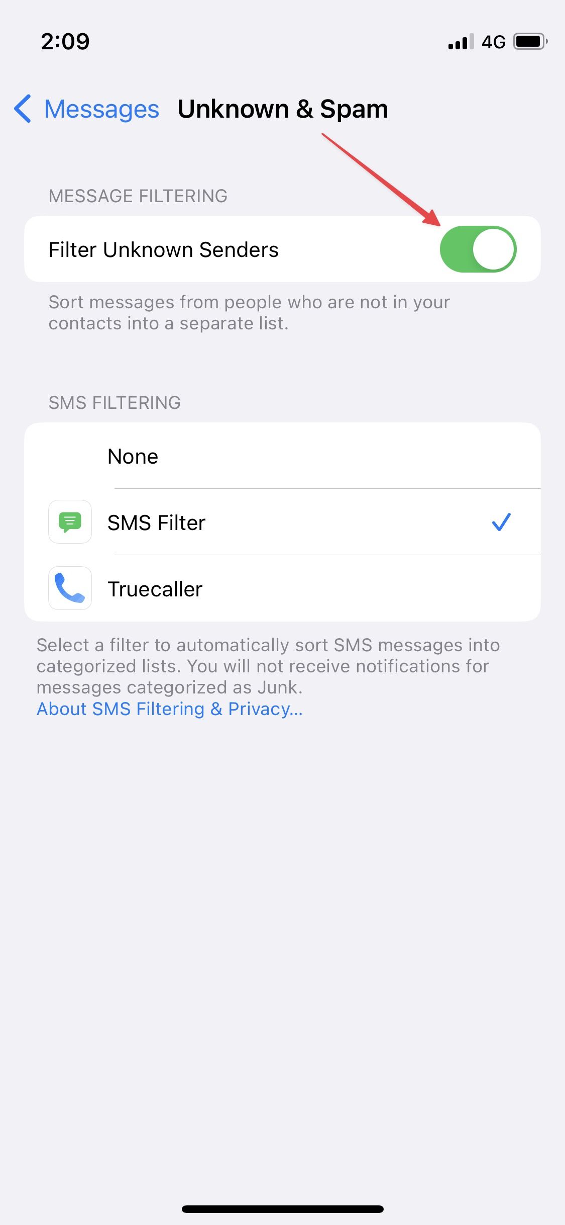 Uma captura de tela mostrando a seção ‘Desconhecido e Spam’ nas configurações do iMessage, com uma seta apontando para a opção ‘Filtrar remetentes desconhecidos’, que está visivelmente ativada, indicando seu status ativo.