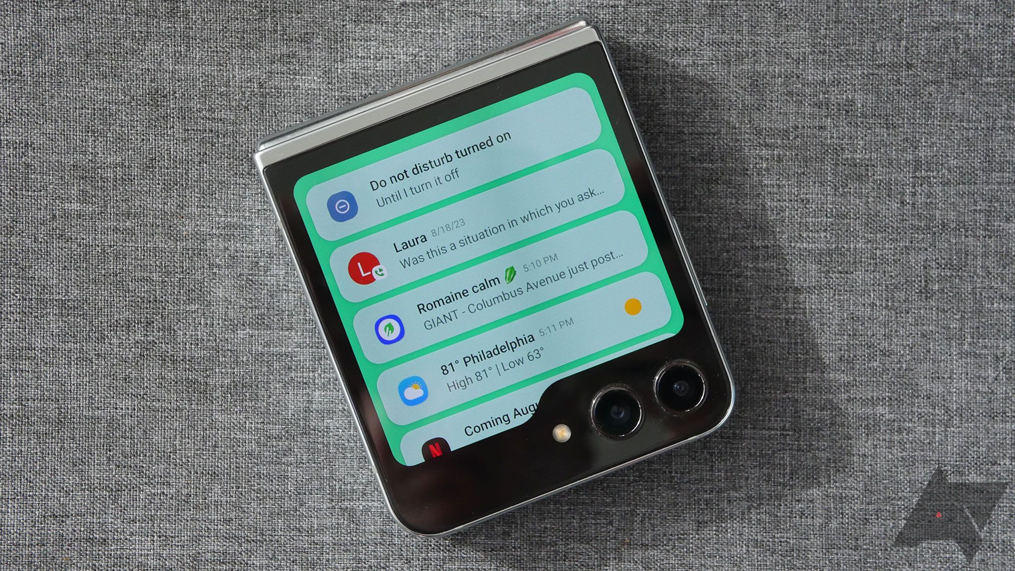 Galaxy Z Flip 5 em um fundo cinza com notificações exibidas.