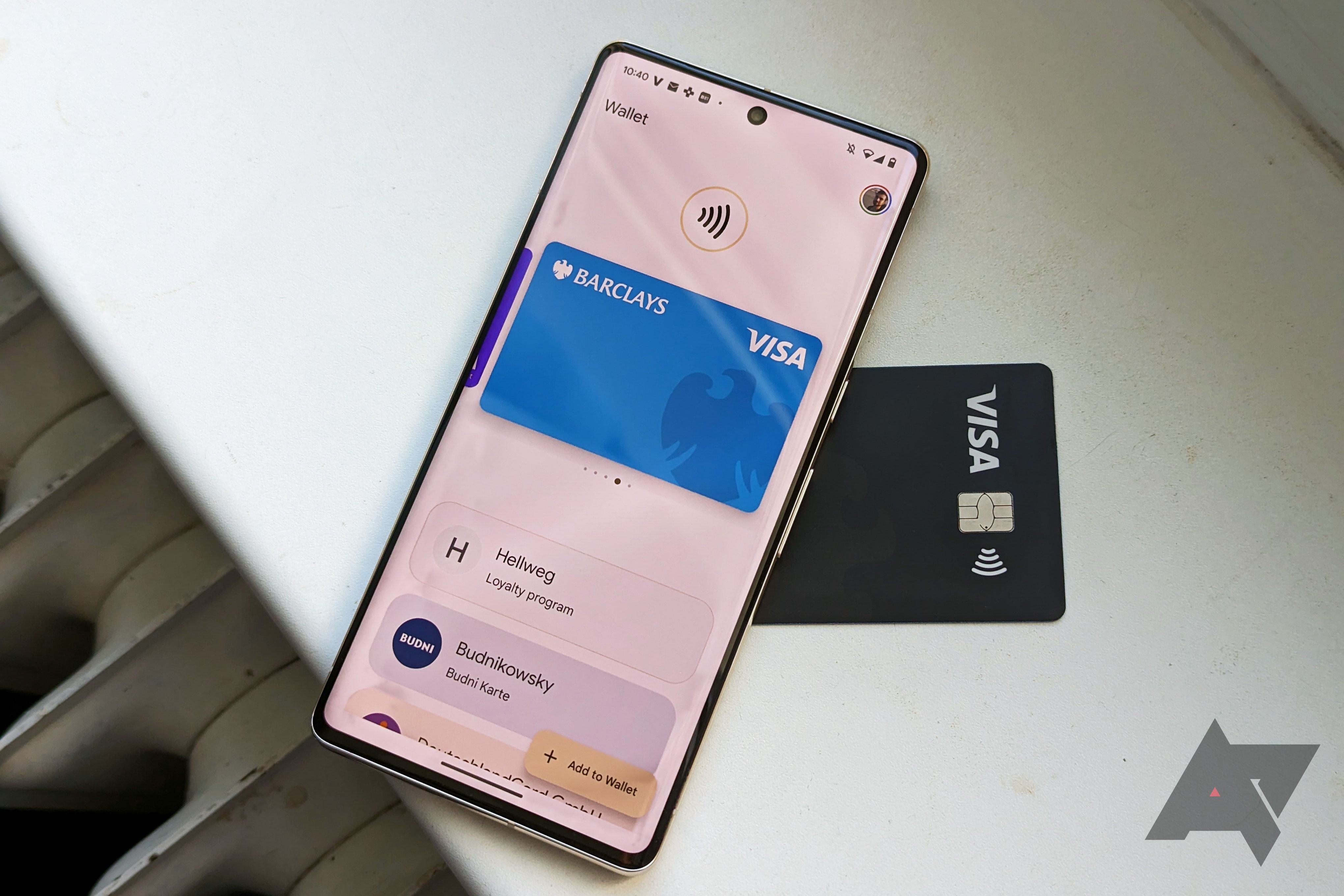 Um smartphone Pixel exibindo a Google Wallet com um cartão Visa azul enquanto o telefone fica sobre um cartão Visa preto real.