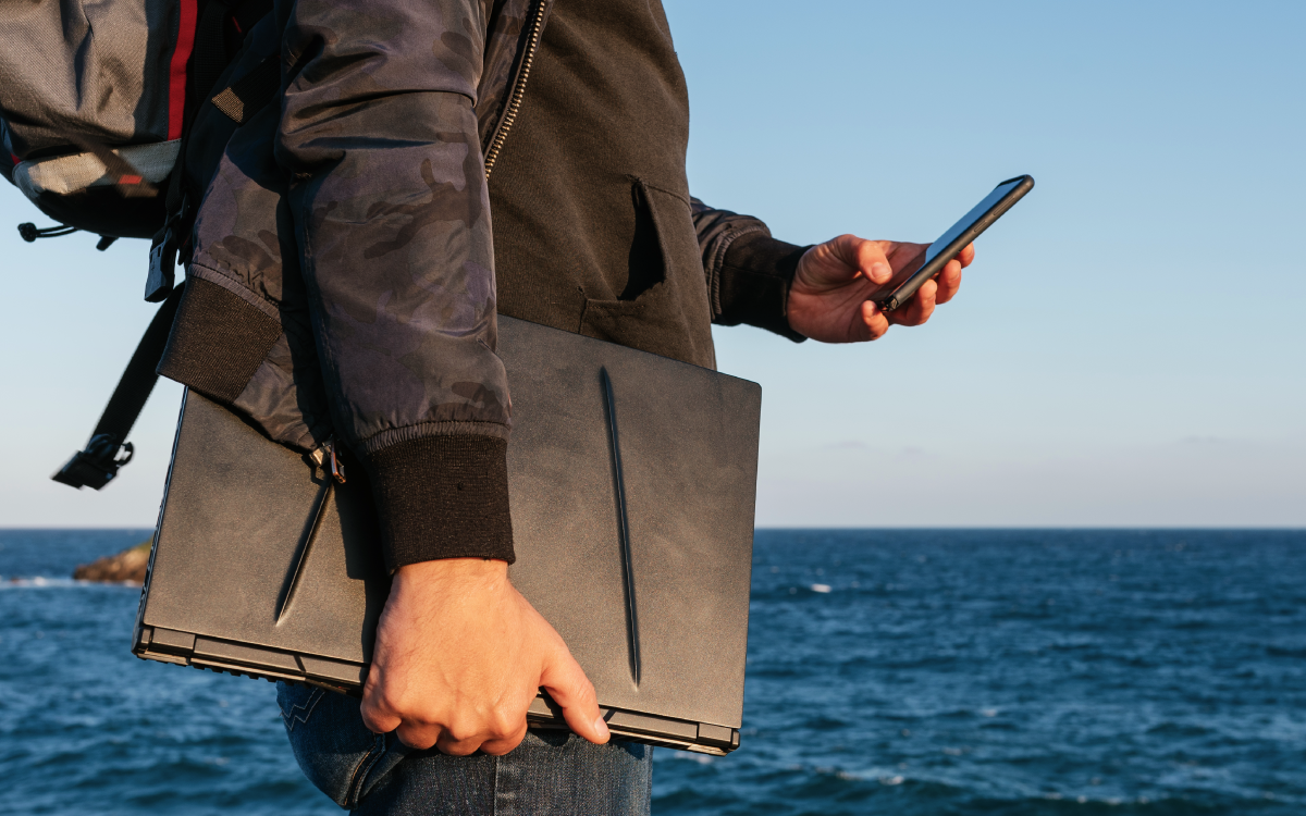 Viajante masculino usando seu telefone à beira-mar.