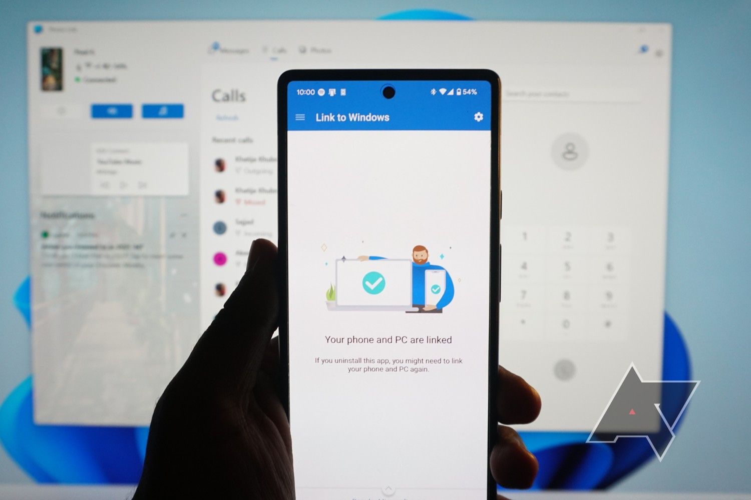 Um smartphone mostrando o aplicativo Link to Windows na tela com uma imagem de um registro de chamadas em segundo plano