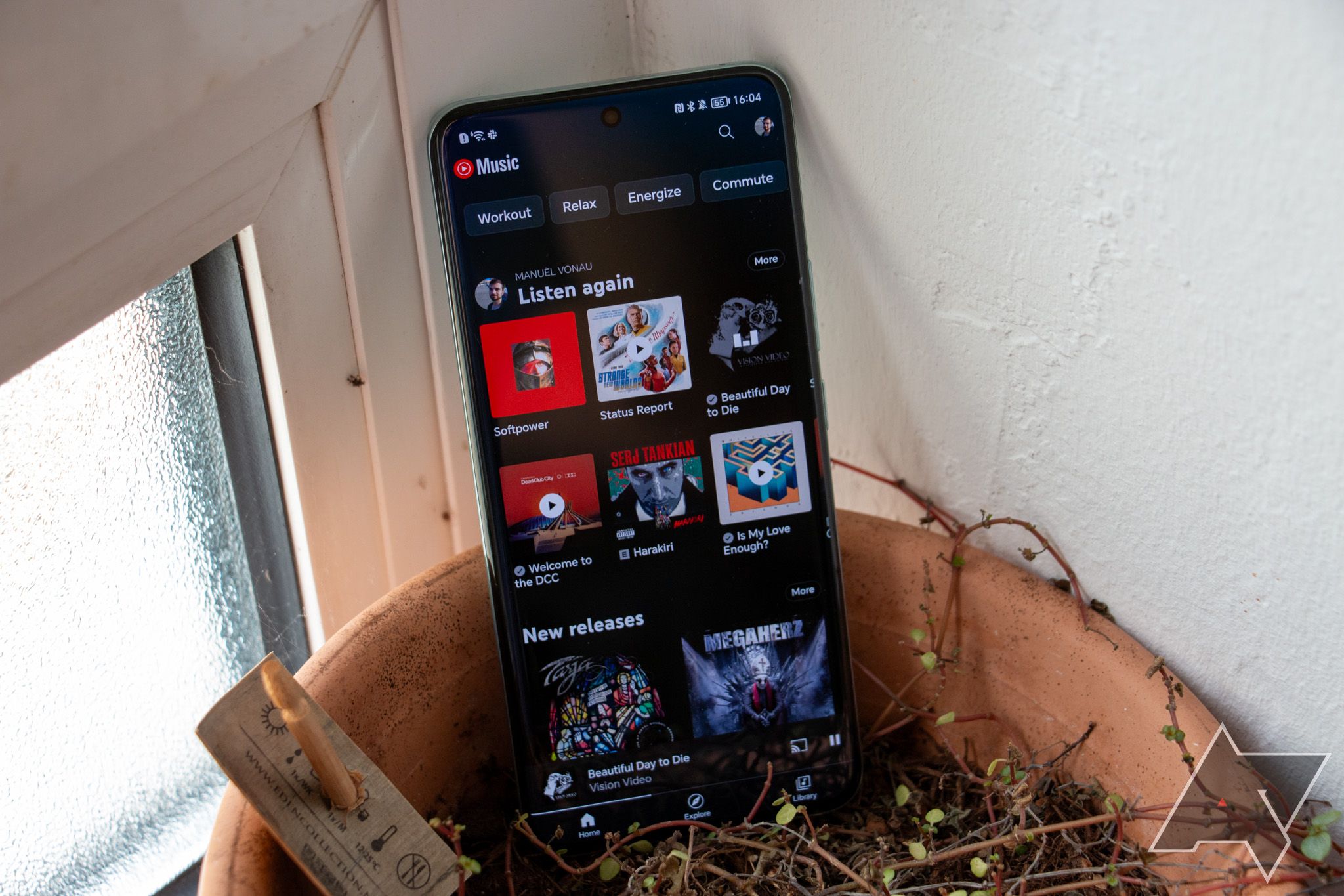 A tela inicial do YouTube Music em um smartphone Android apoiada em uma panela de barro.