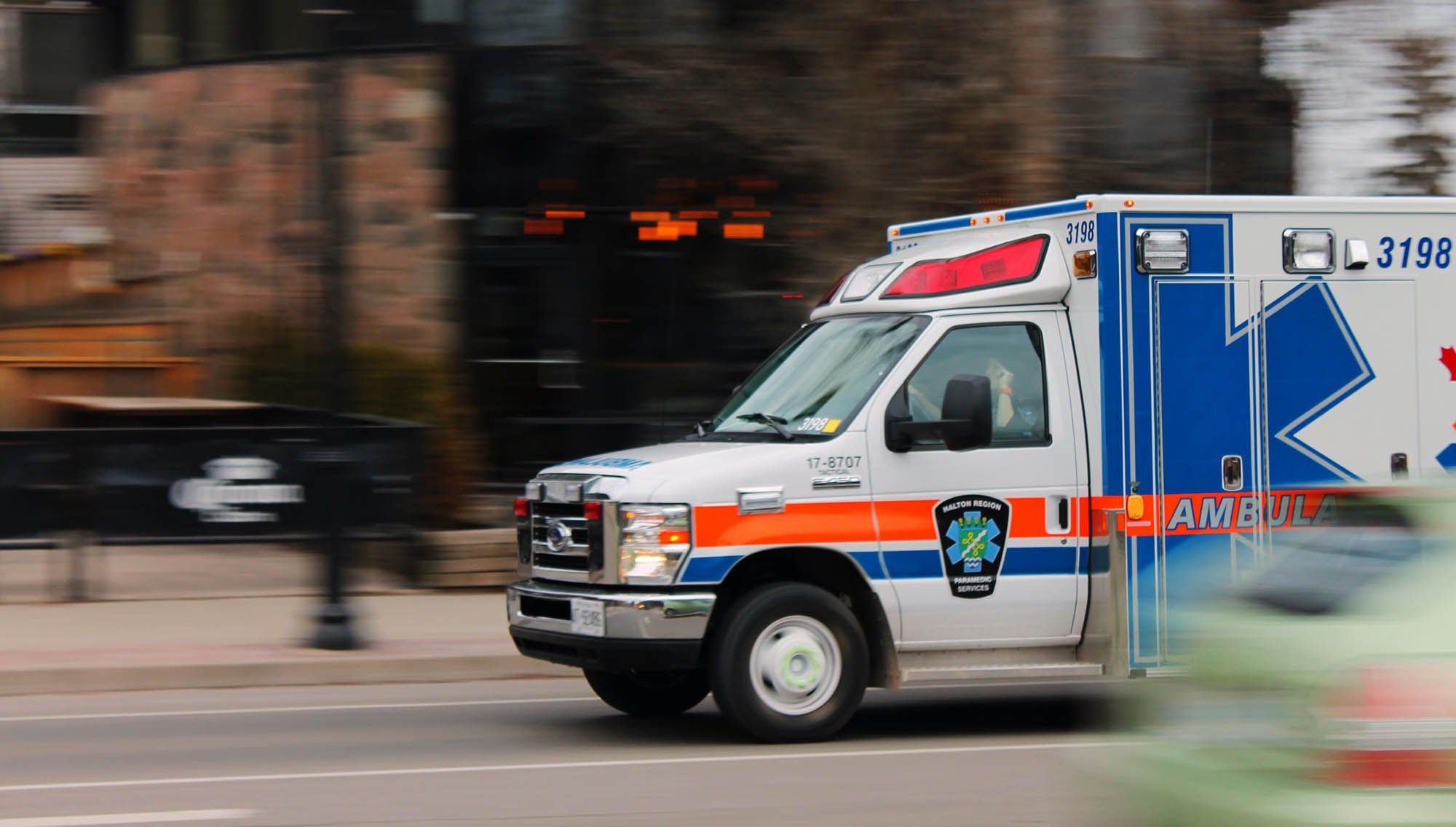 Uma ambulância correndo pela rua em meio a um fundo desfocado