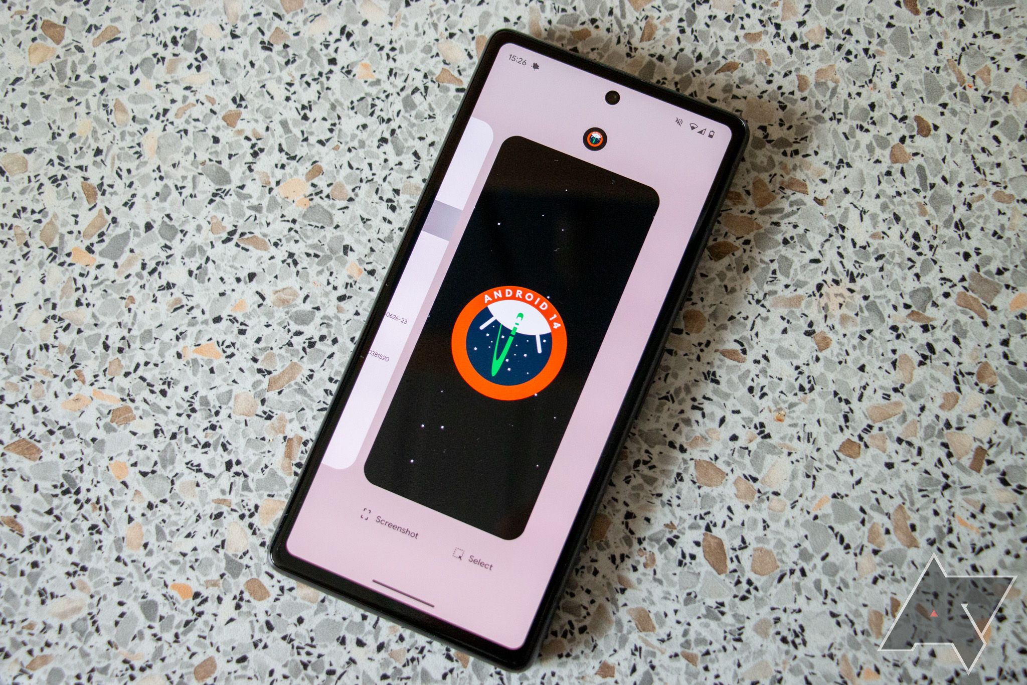 telefone pixel mostrando papel de parede do Android 14 apoiado em uma superfície de pedra