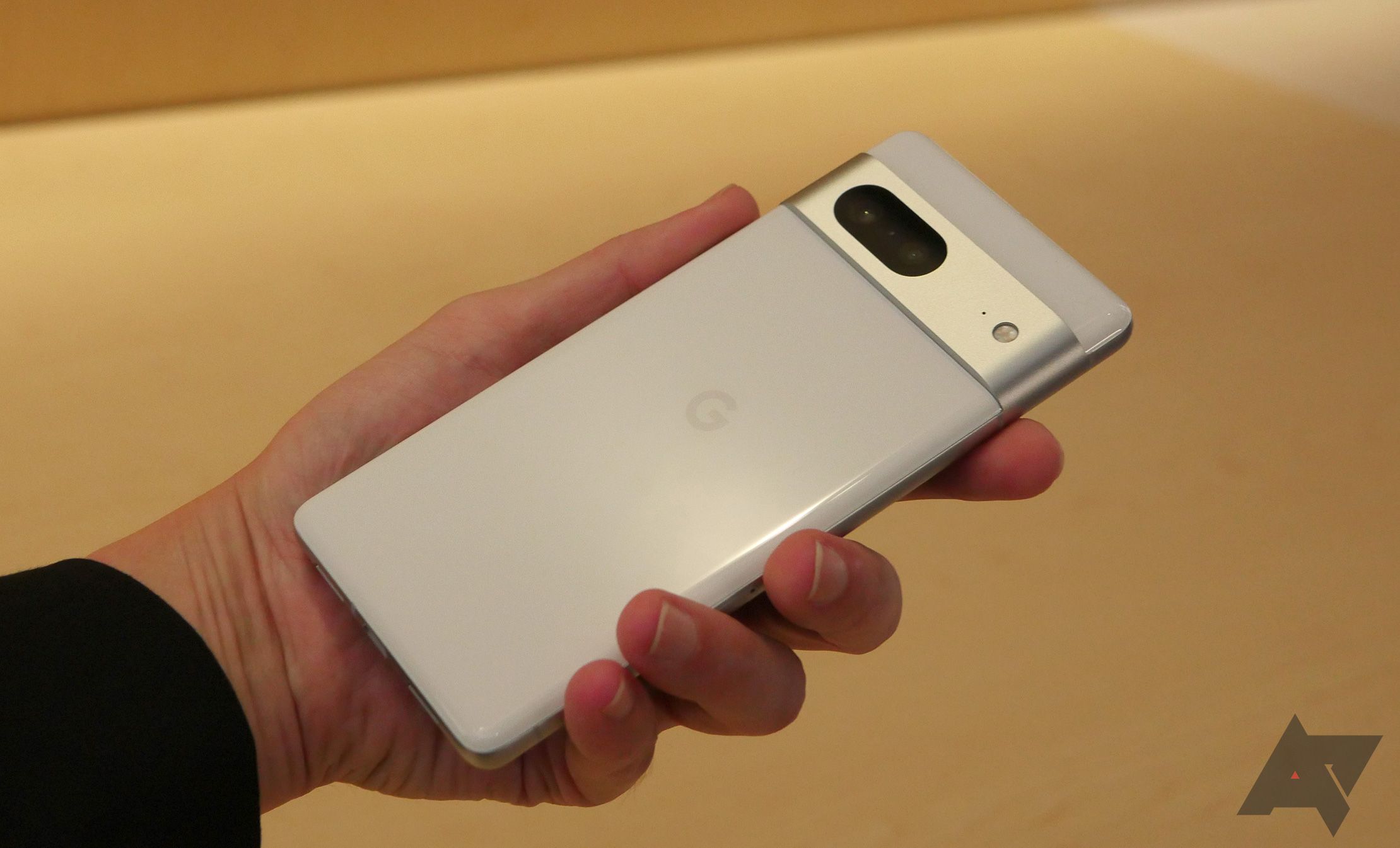 Google Pixel 7 de cor branca sendo segurado com a mão esquerda