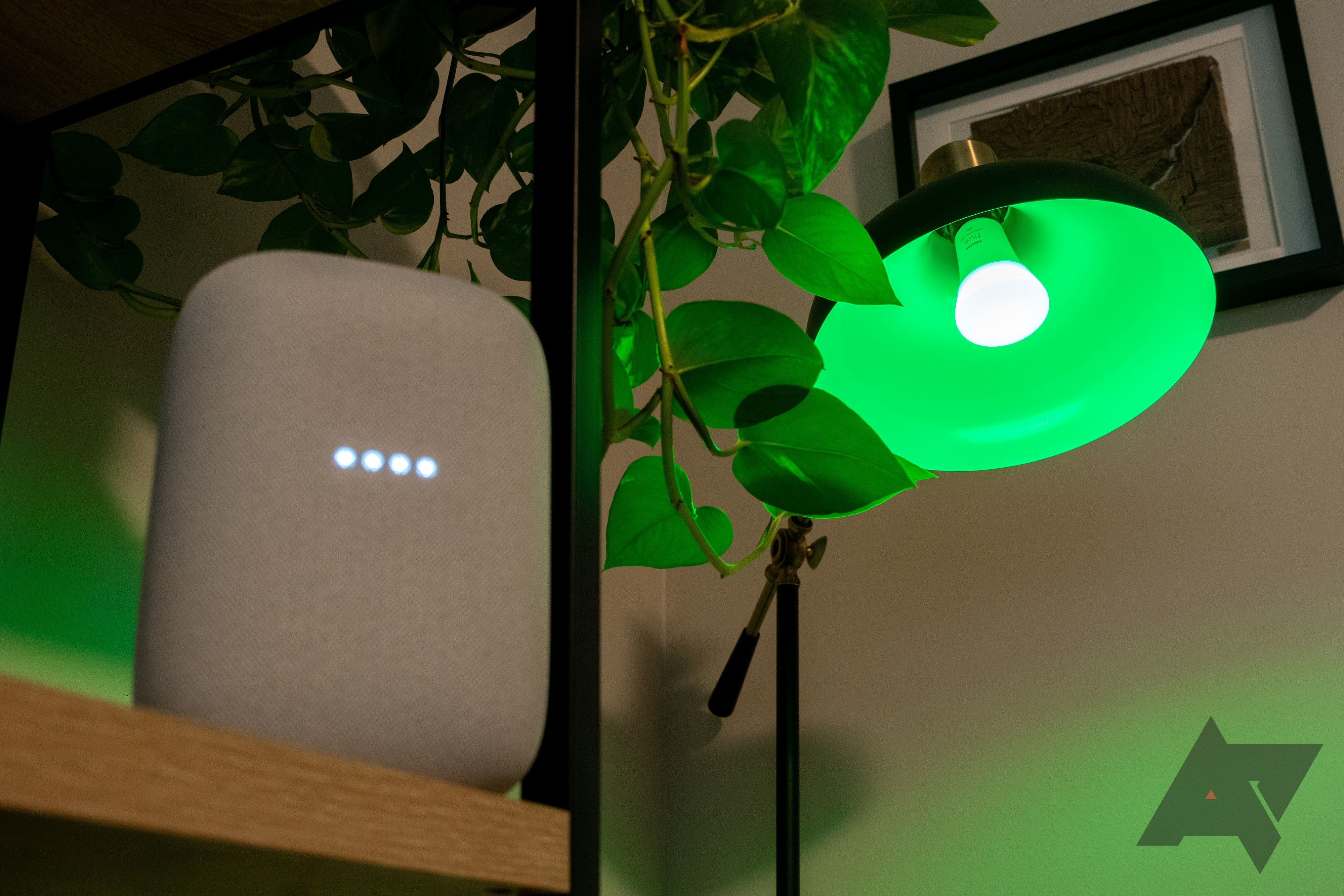 Uma lâmpada Phillips Hue verde ao lado de um alto-falante Google Nest