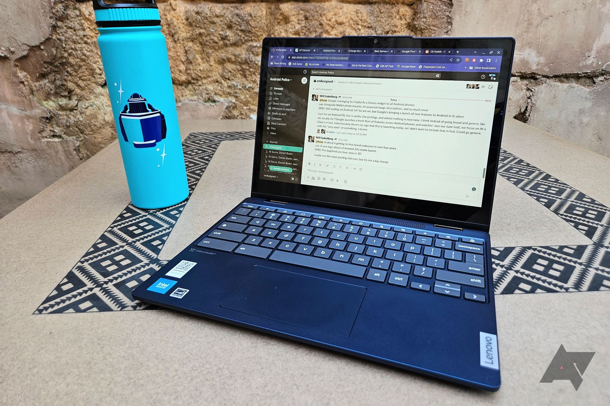 Um Chromebook Lenovo Flex 3i (8ª geração) em uma mesa com um padrão de mosaico ao lado de uma garrafa de água azul