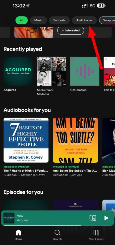 Uma seta vermelha aponta para o menu Audiolivros no aplicativo Spotify