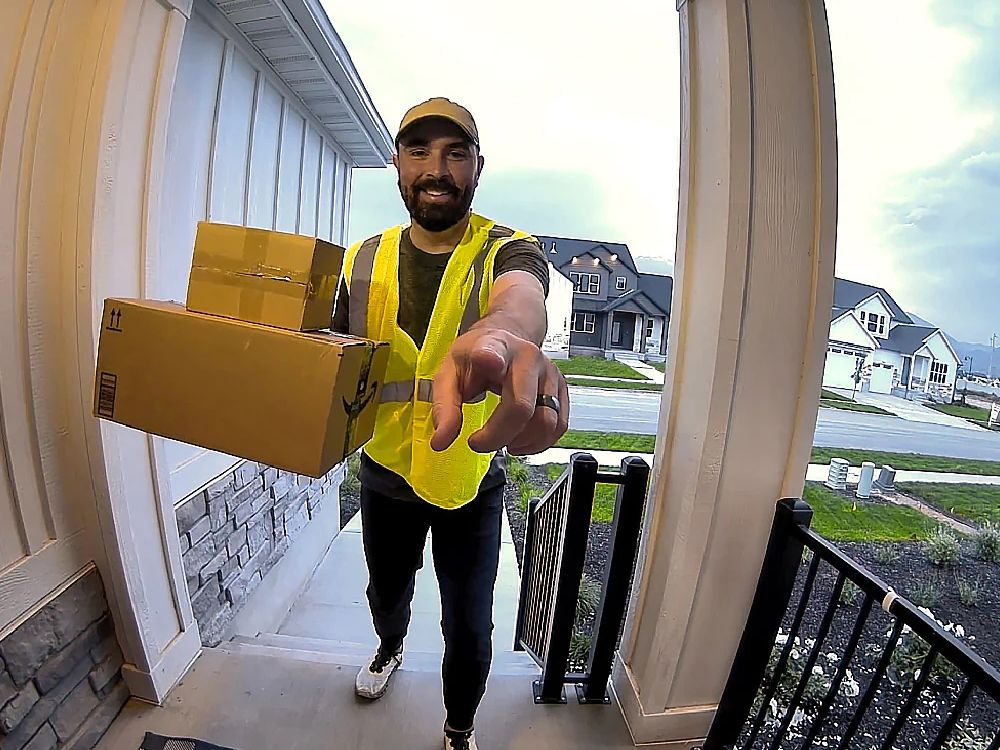 Ponto de vista da câmera Wyze Video Doorbell V3 de uma pessoa deixando pacotes em uma varanda