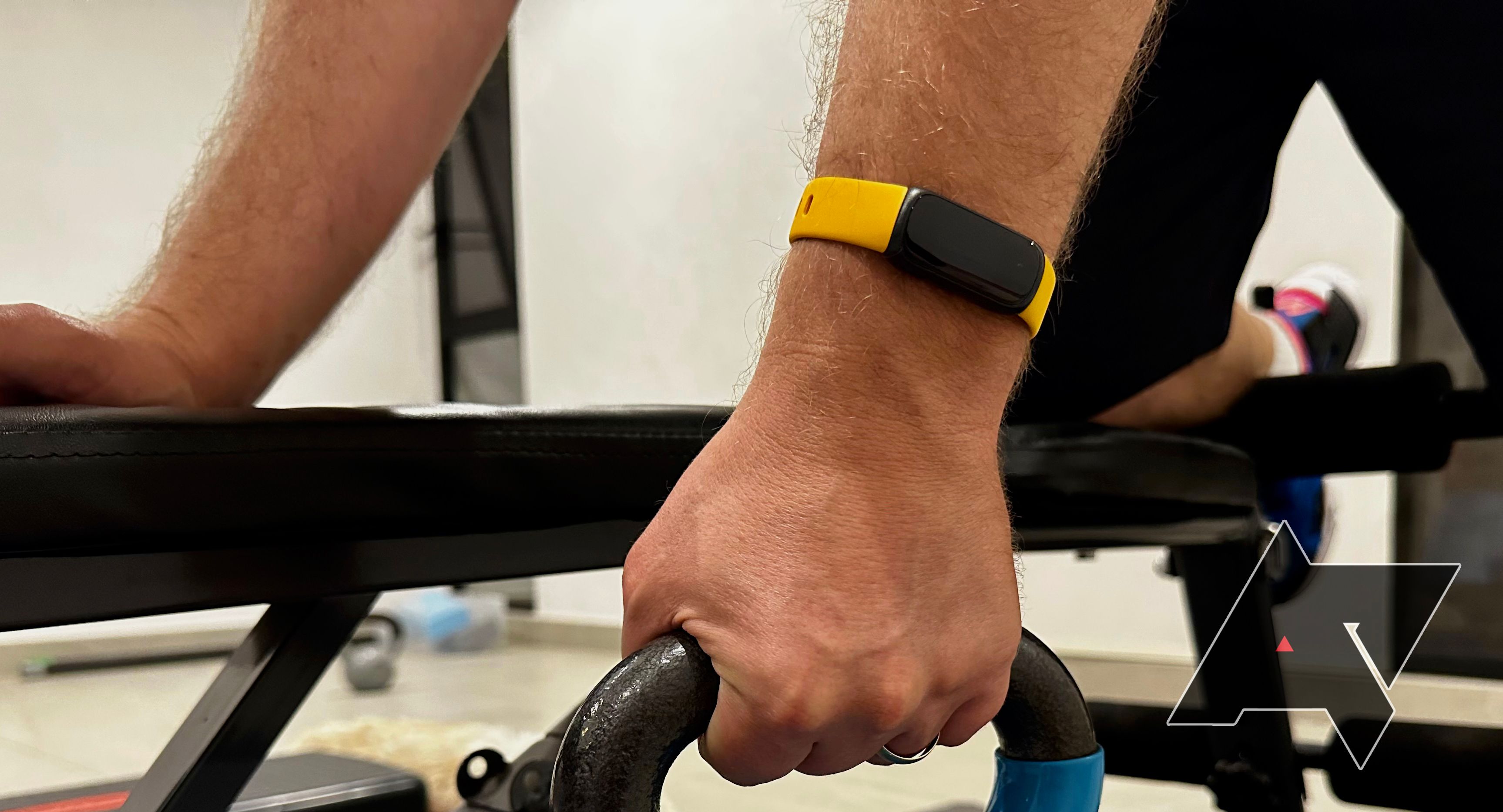 Mão segurando um kettlebell, usando um Fitbit Inspire 3