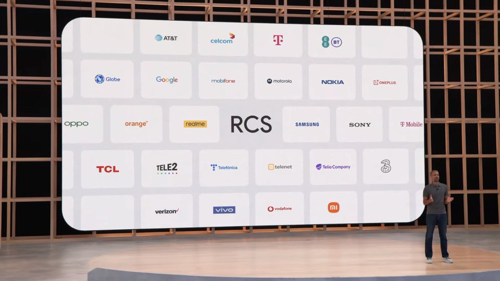 Um apresentador no palco em frente a uma tela mostrando os parceiros RCS do Google