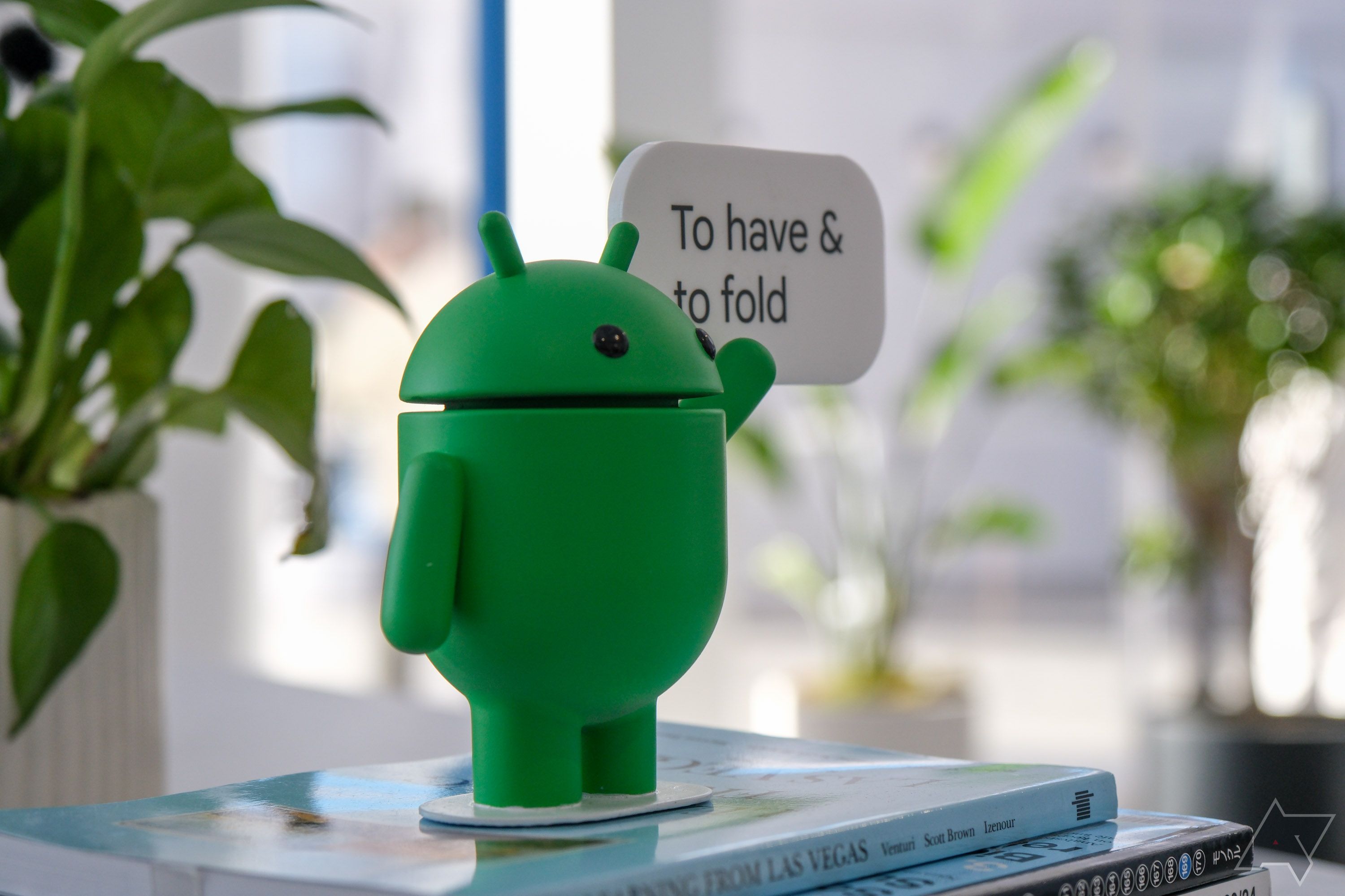 Um mascote do Android com uma placa que diz ‘Ter e dobrar’