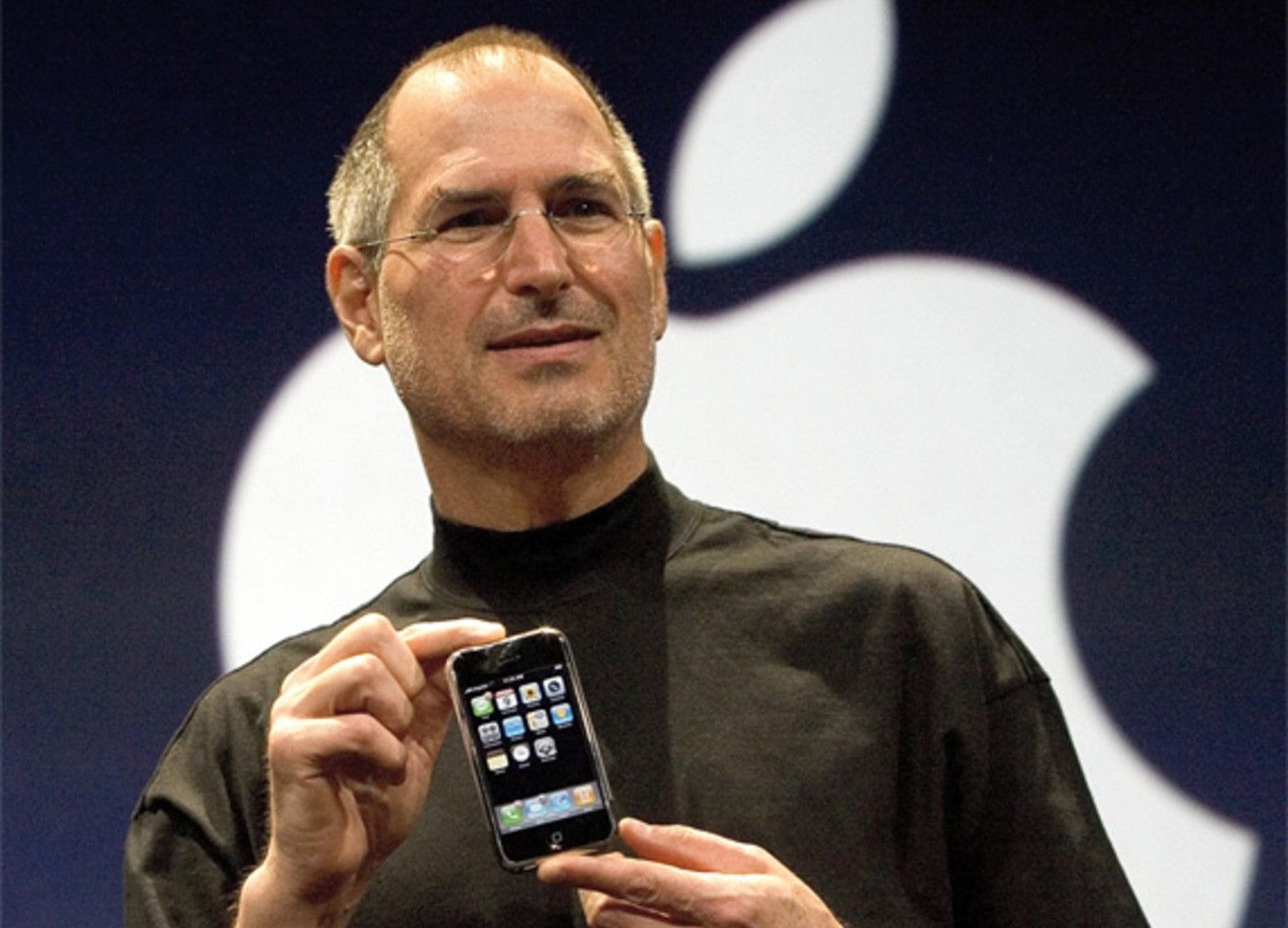 Steve Jobs segurando o primeiro iphone durante a apresentação principal em 2007.