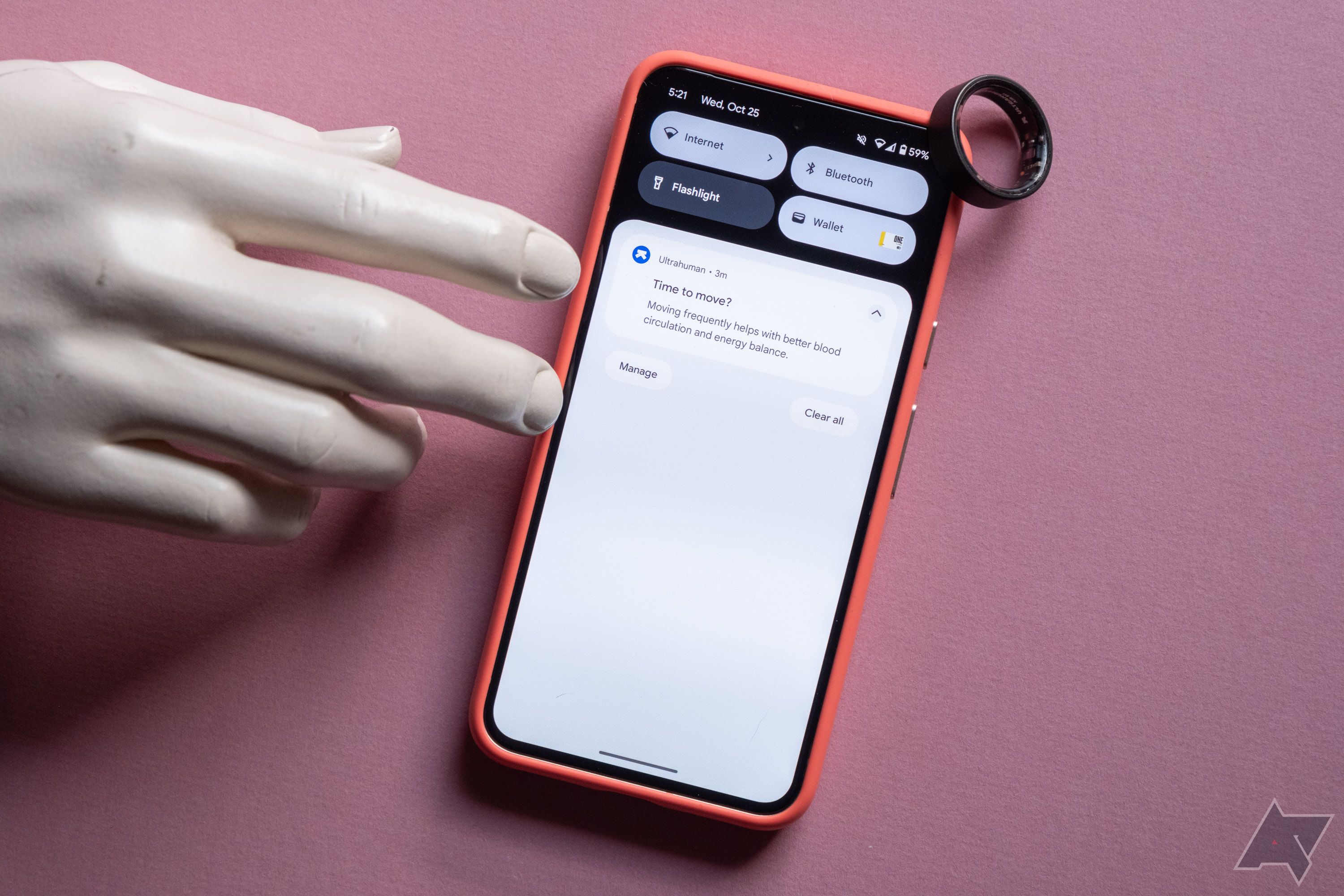 Uma mão tocando um smartphone ao lado de um anel inteligente
