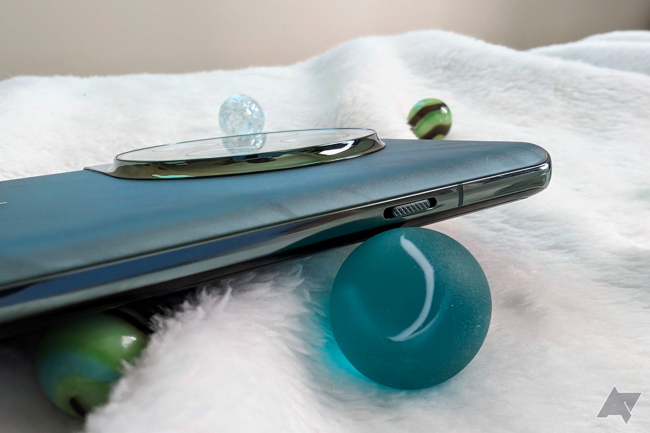 Controle deslizante de alerta OnePlus 12 em um cobertor felpudo com bolinhas de gude coloridas ao redor