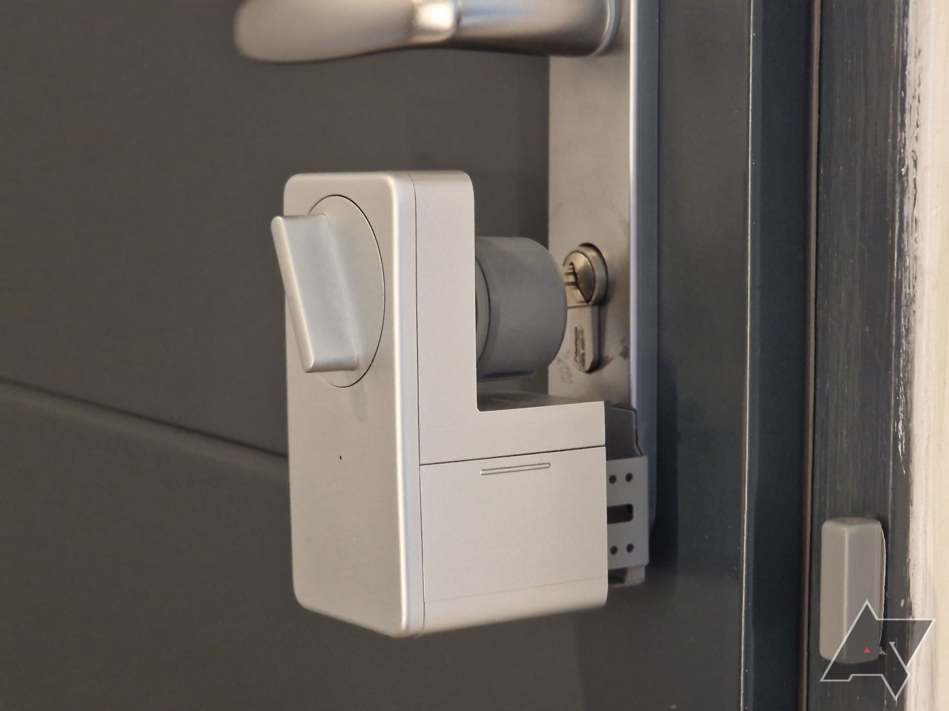 Imagem do SwitchBot Smart Lock anexado à porta, com o sensor da porta na lateral