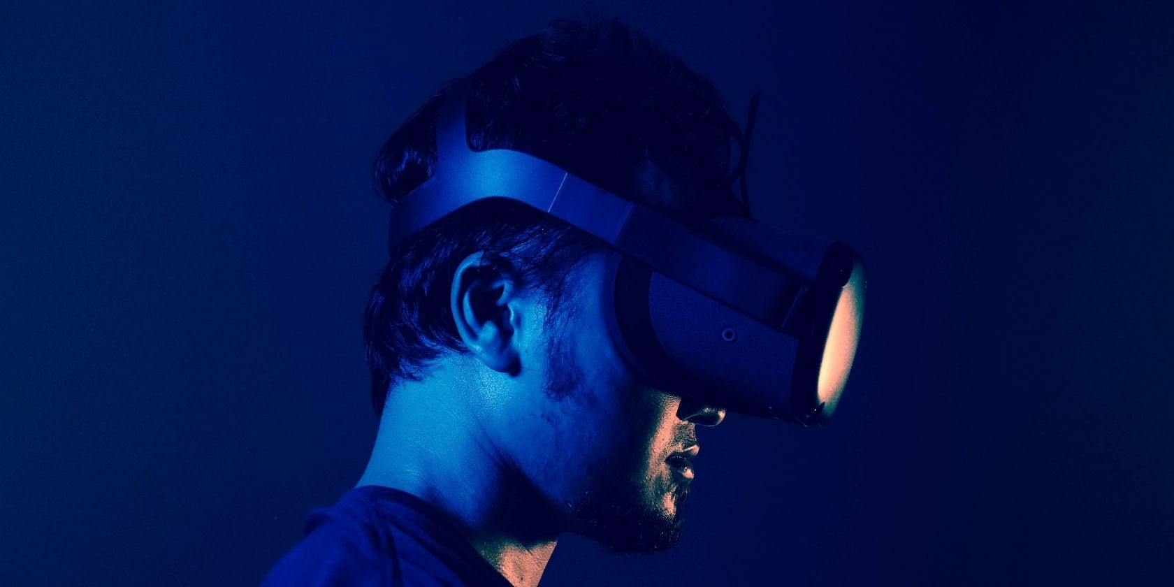 Homem usando óculos de realidade virtual em luz azul.
