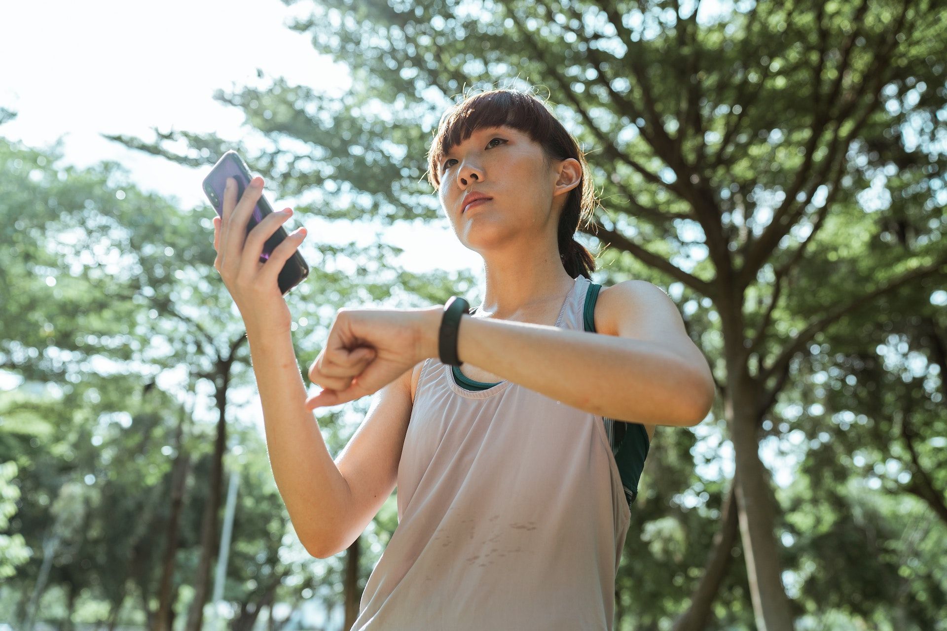 Uma pessoa para durante o treino para verificar a frequência cardíaca usando um telefone e um smartwatch.