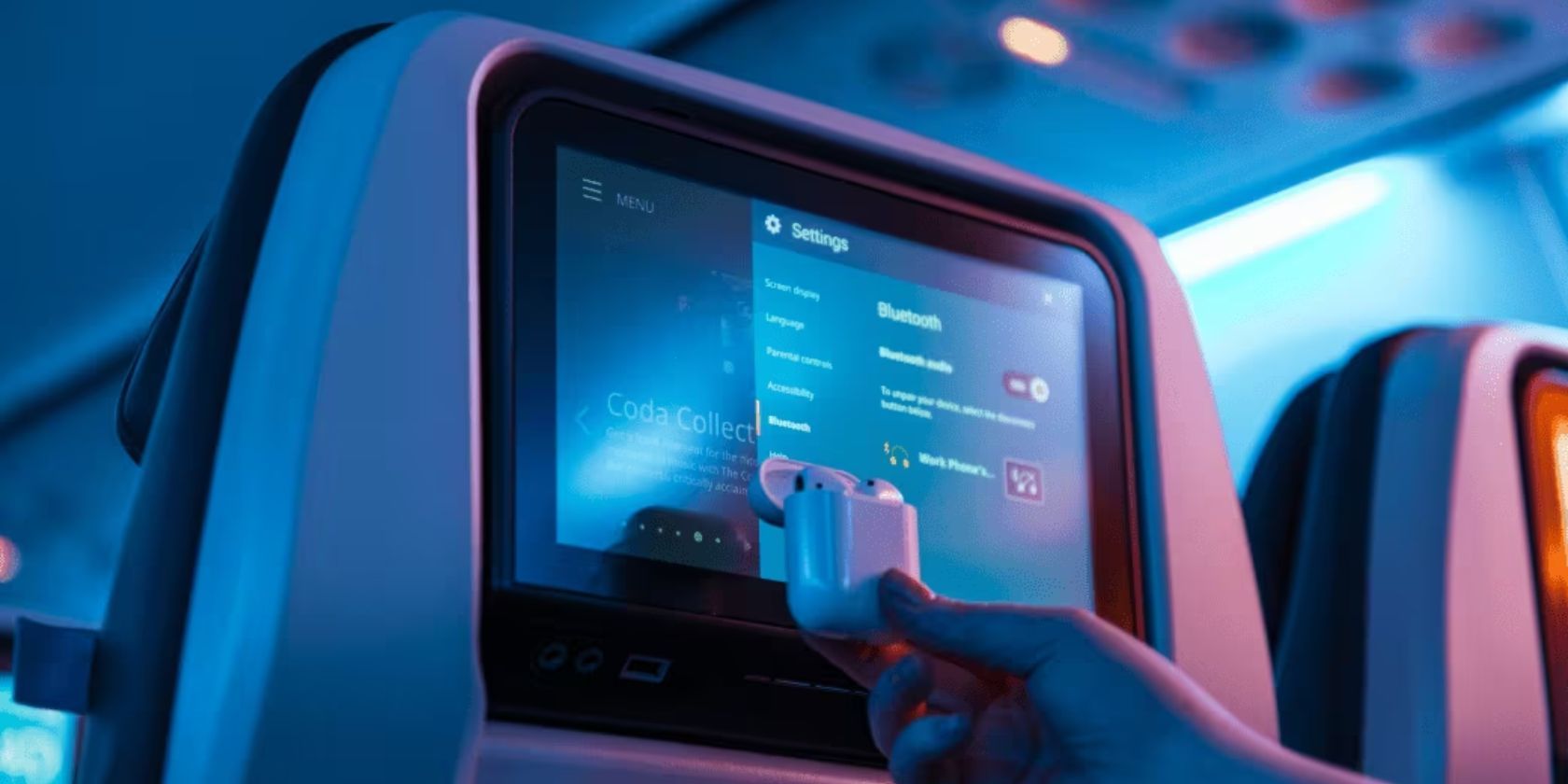 mão segurando airpods na tela do encosto do avião