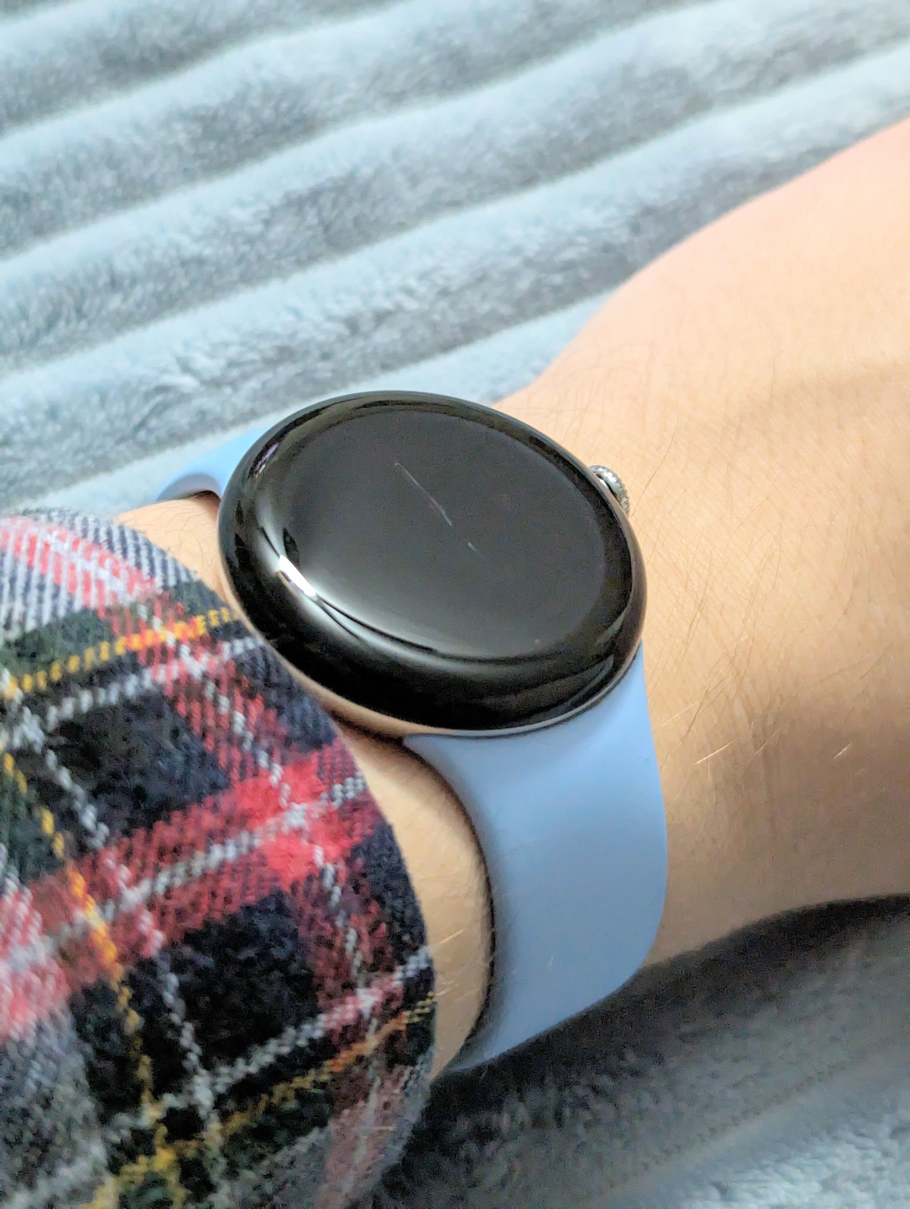 Um Google Pixel Watch 2 no pulso de alguém com um arranhão no meio da tela