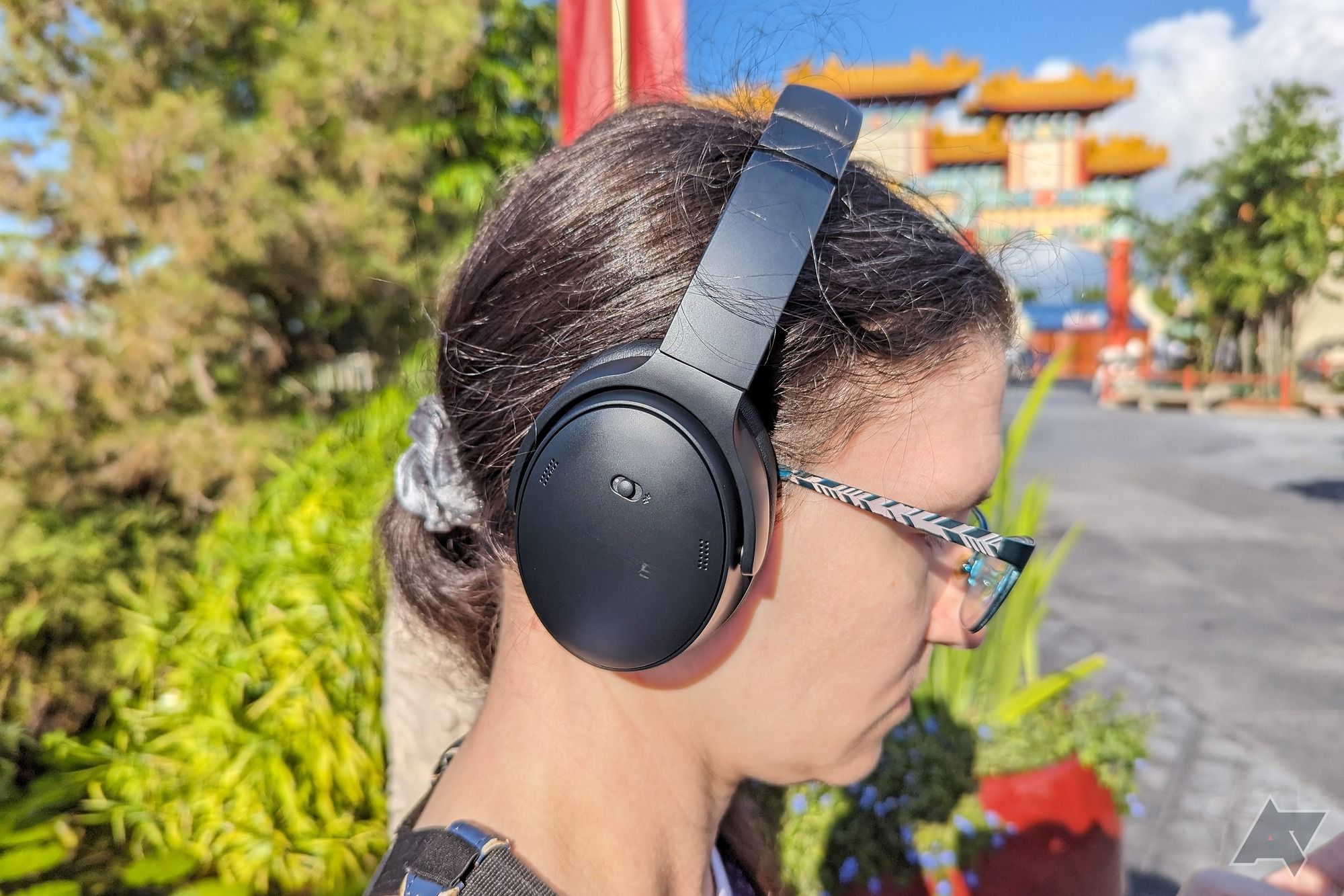 Um Ara Wagoner de cabelos crespos usando fones de ouvido Bose QuietComfort em um pavilhão vazio da China no Epcot 