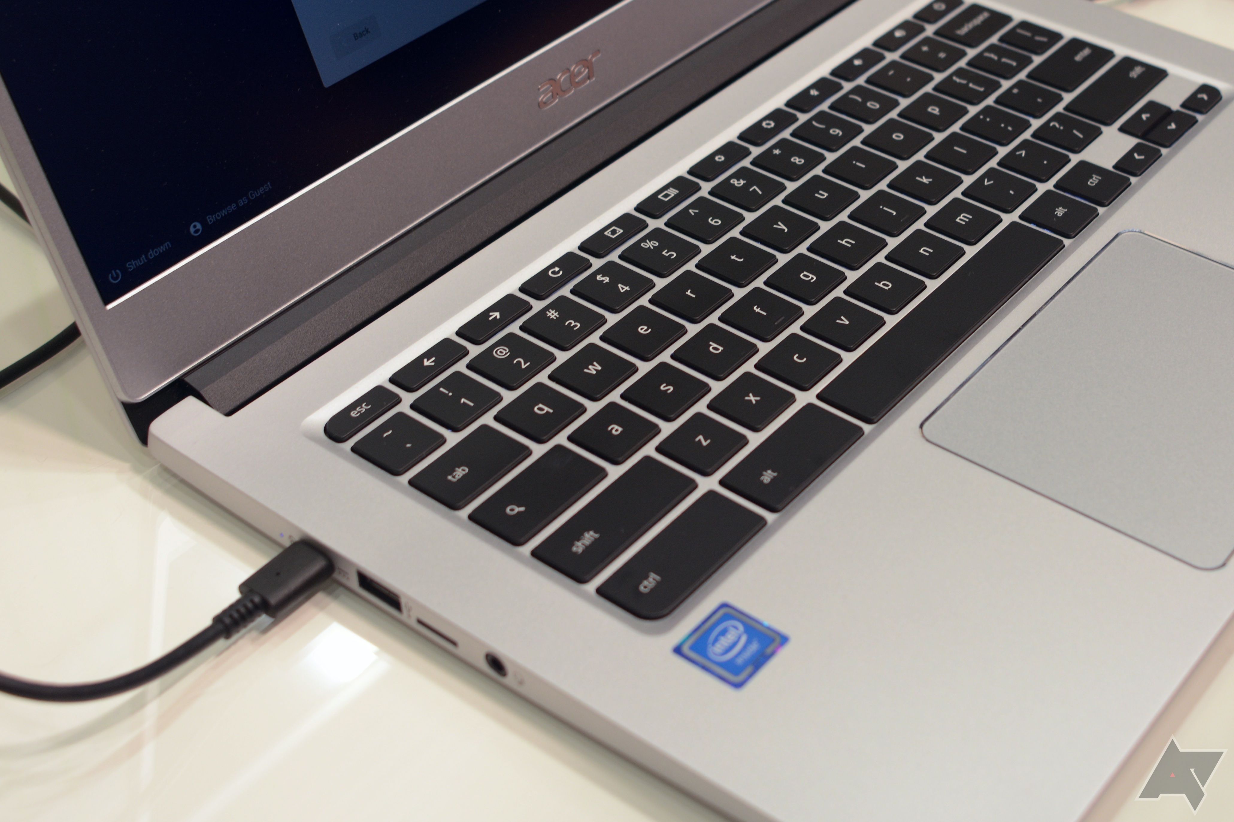 Um Chromebook Acer aberto carregando via USB-C em uma superfície branca