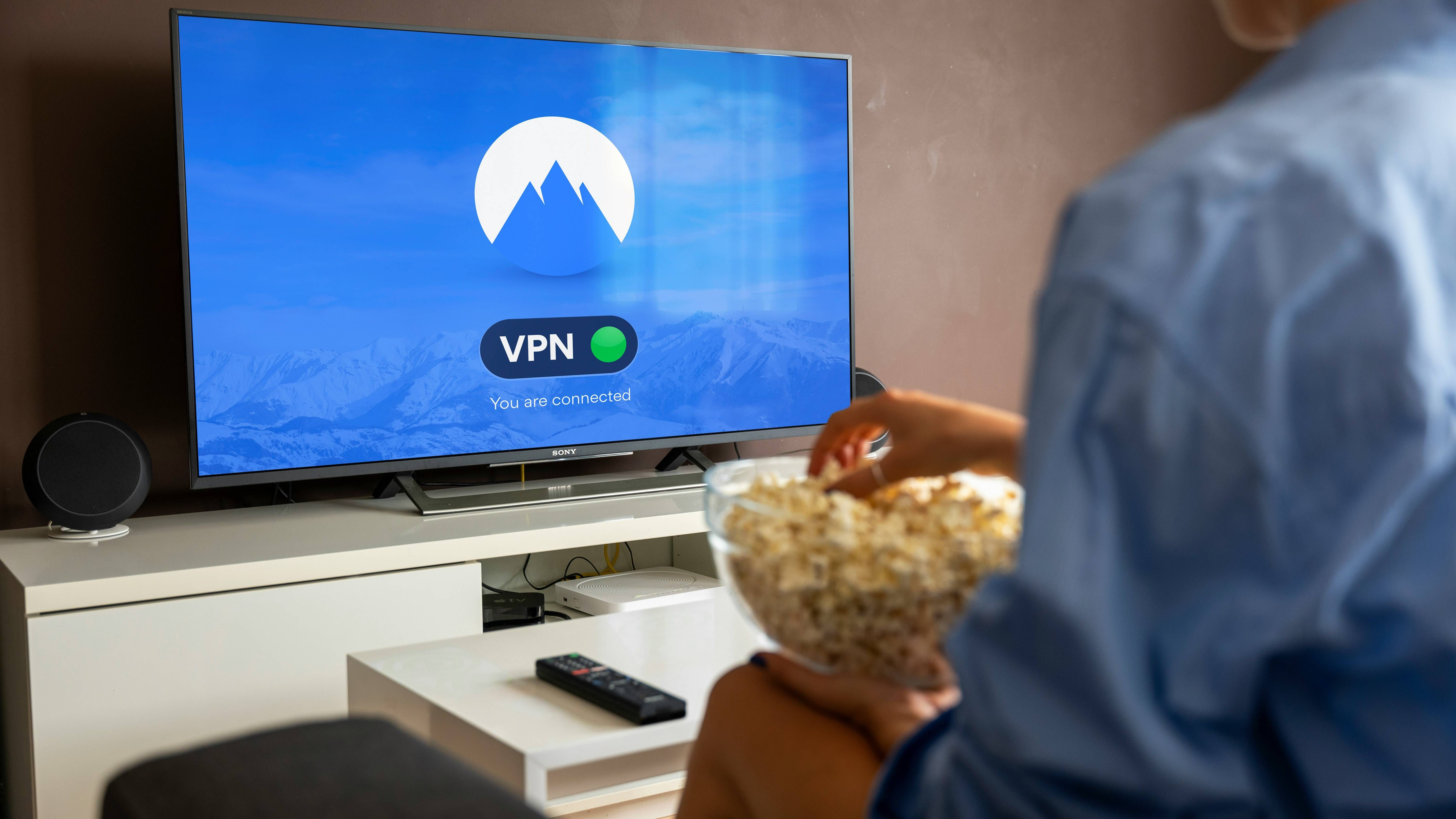 Pessoa com pipoca assistindo TV de tela plana preta ligada na tela VPN conectada