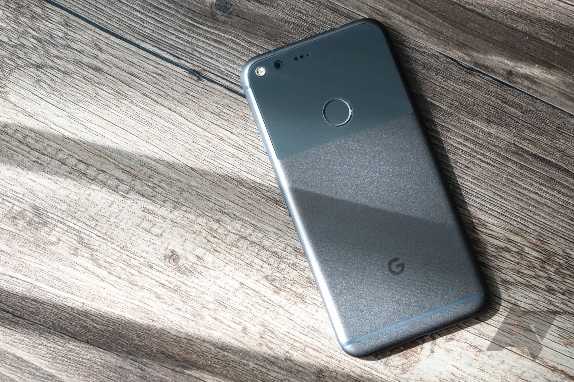 Um smartphone Google Pixel de primeira geração virado para baixo em uma superfície de madeira