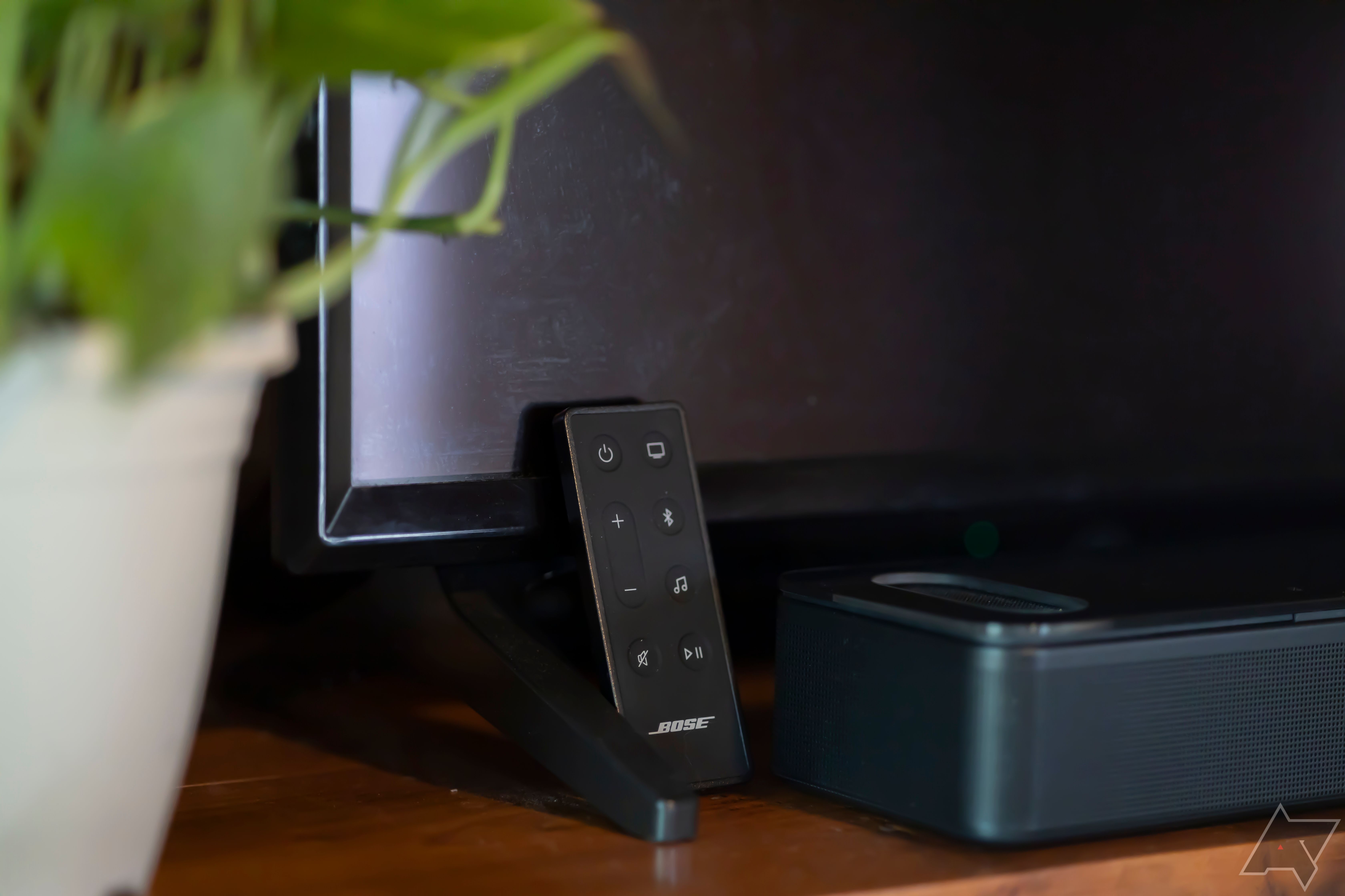 Controle remoto Bose Smart Ultra Soundbar próximo à barra de som e TV