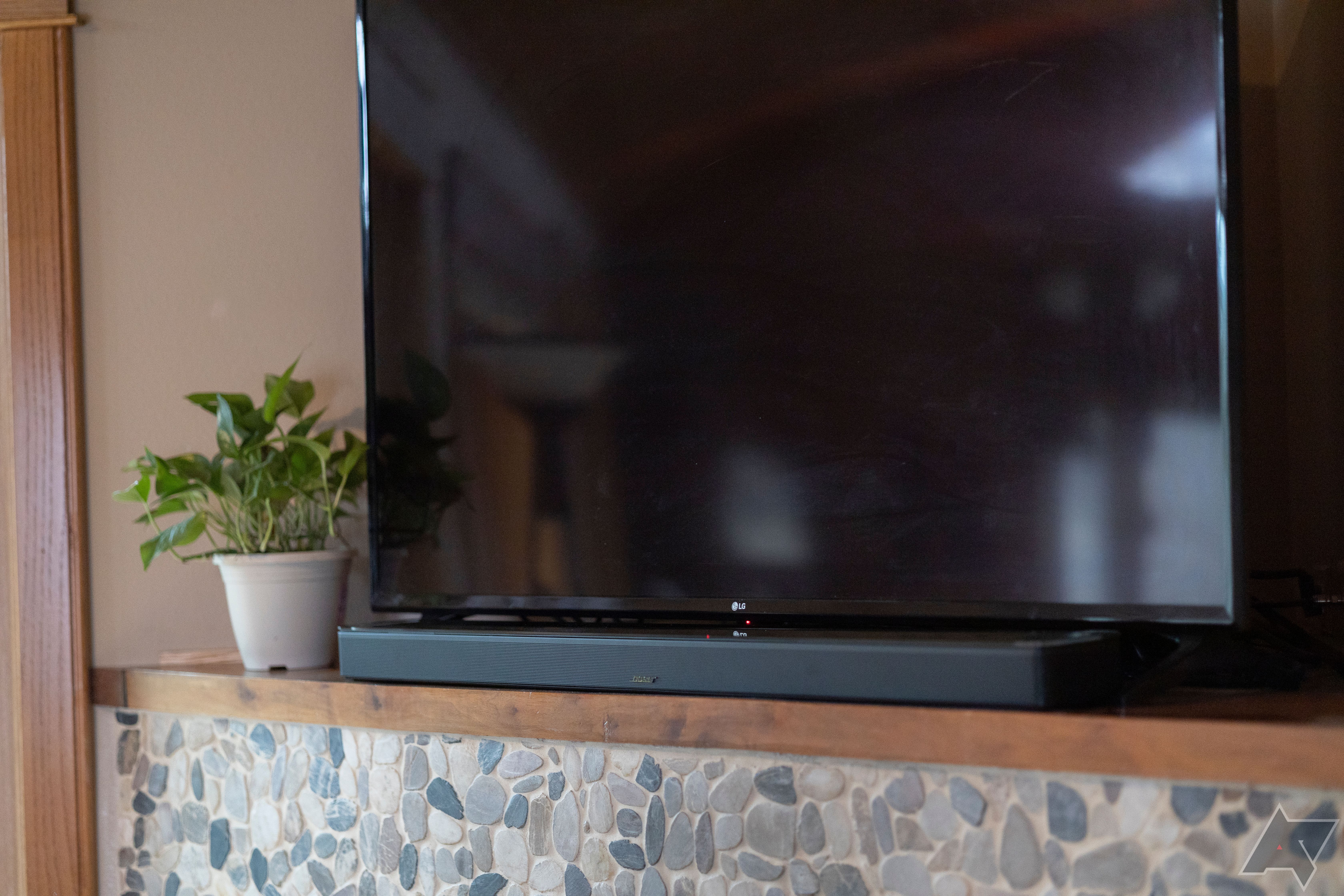 Bose Smart Ultra Soundbar no manto ao lado da planta e da TV