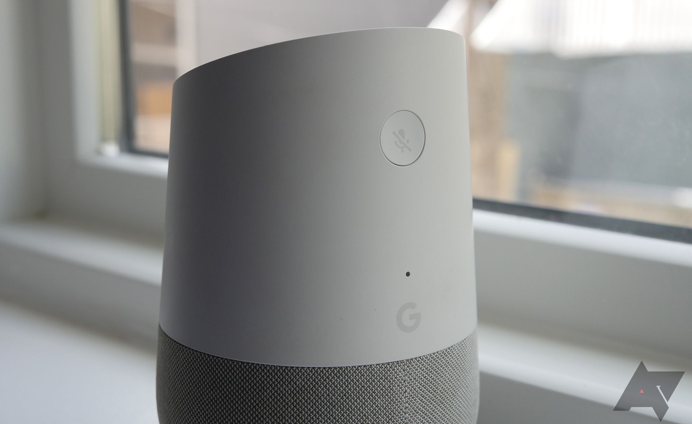 A parte traseira de um alto-falante Google Home de primeira geração mostrando o botão de desligar o microfone