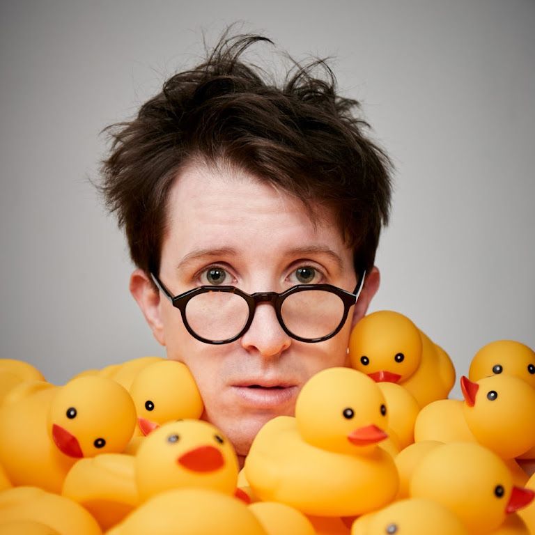 Foto do comediante James Veitch cercado por patos