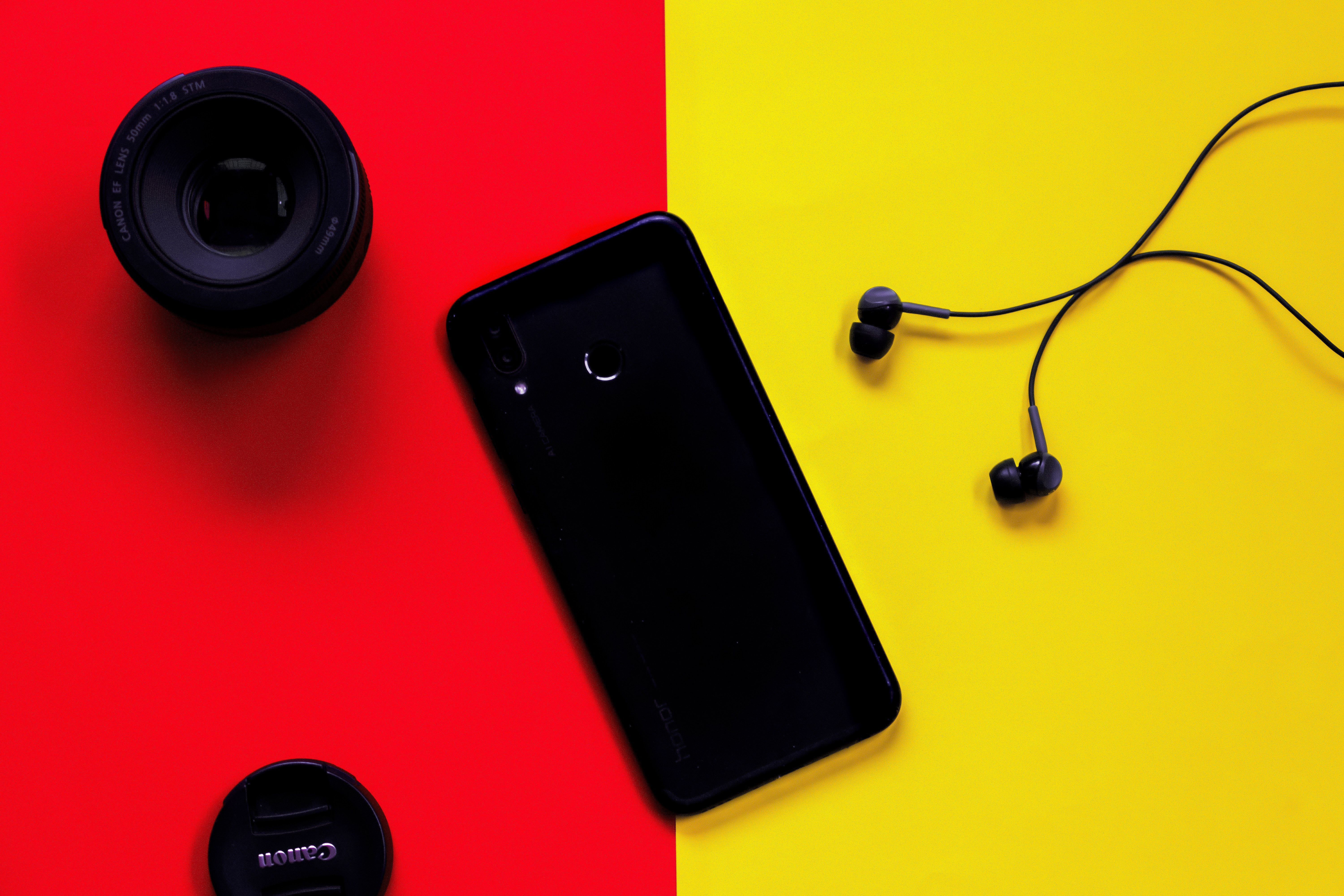 Smartphone preto além de fones de ouvido e lentes de câmera