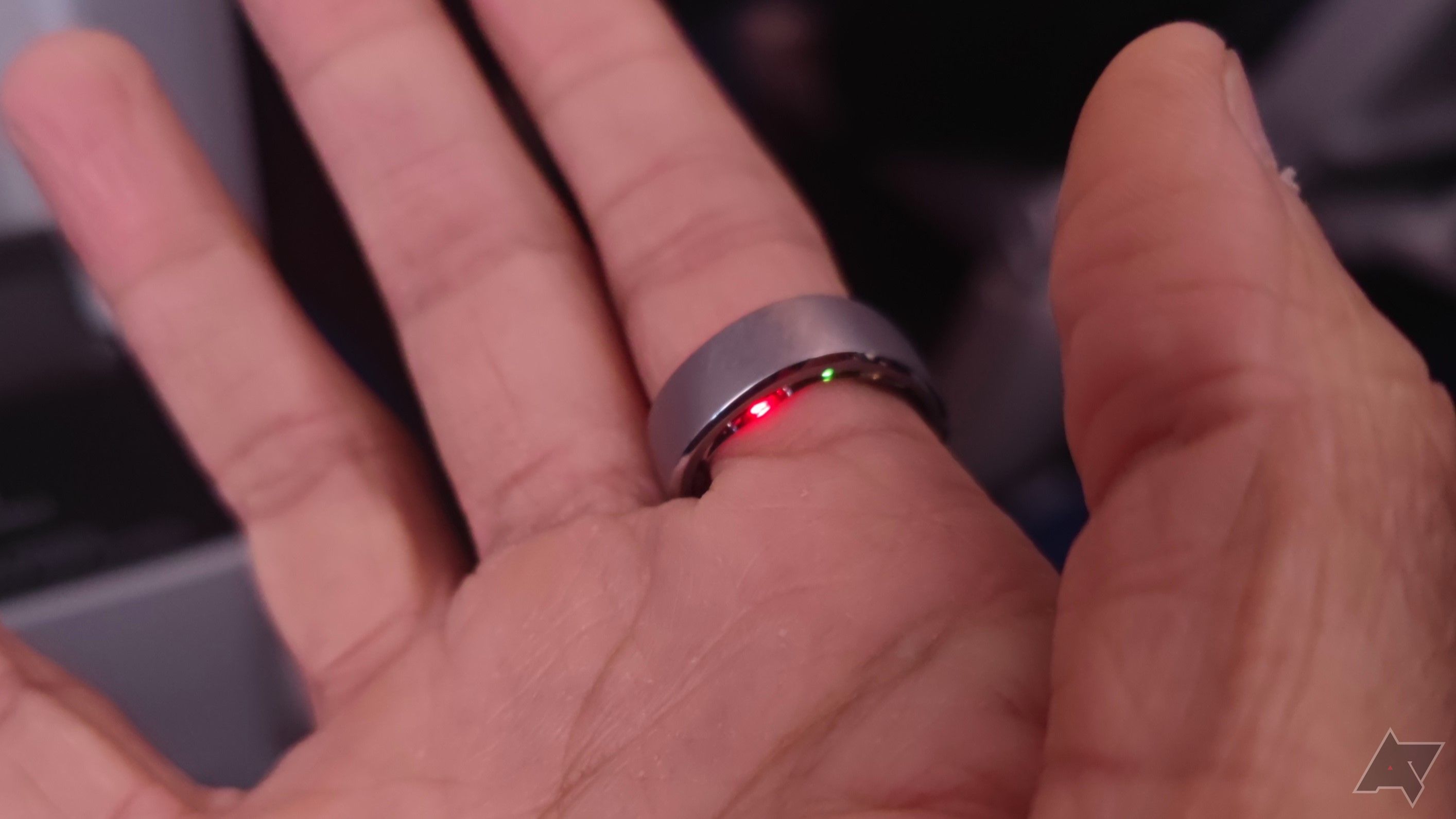 Uma mão usando um anel inteligente com sensores iluminados