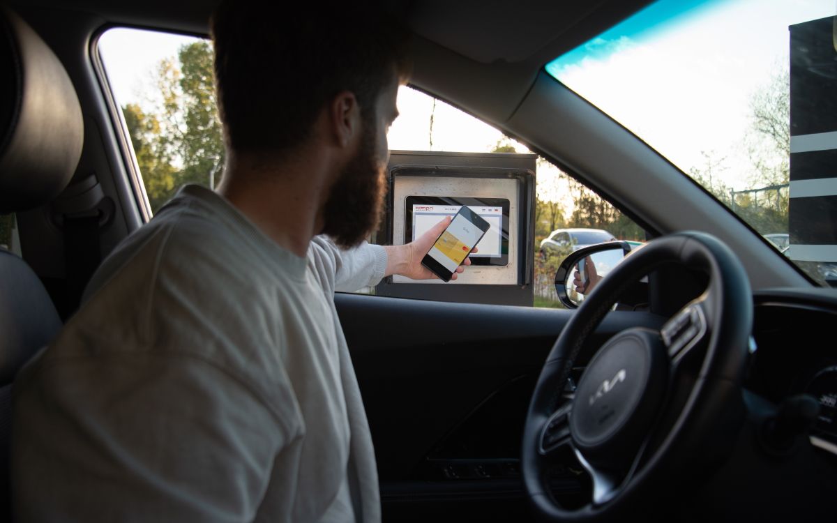 Um homem usando seu telefone para pagar em um drive thru