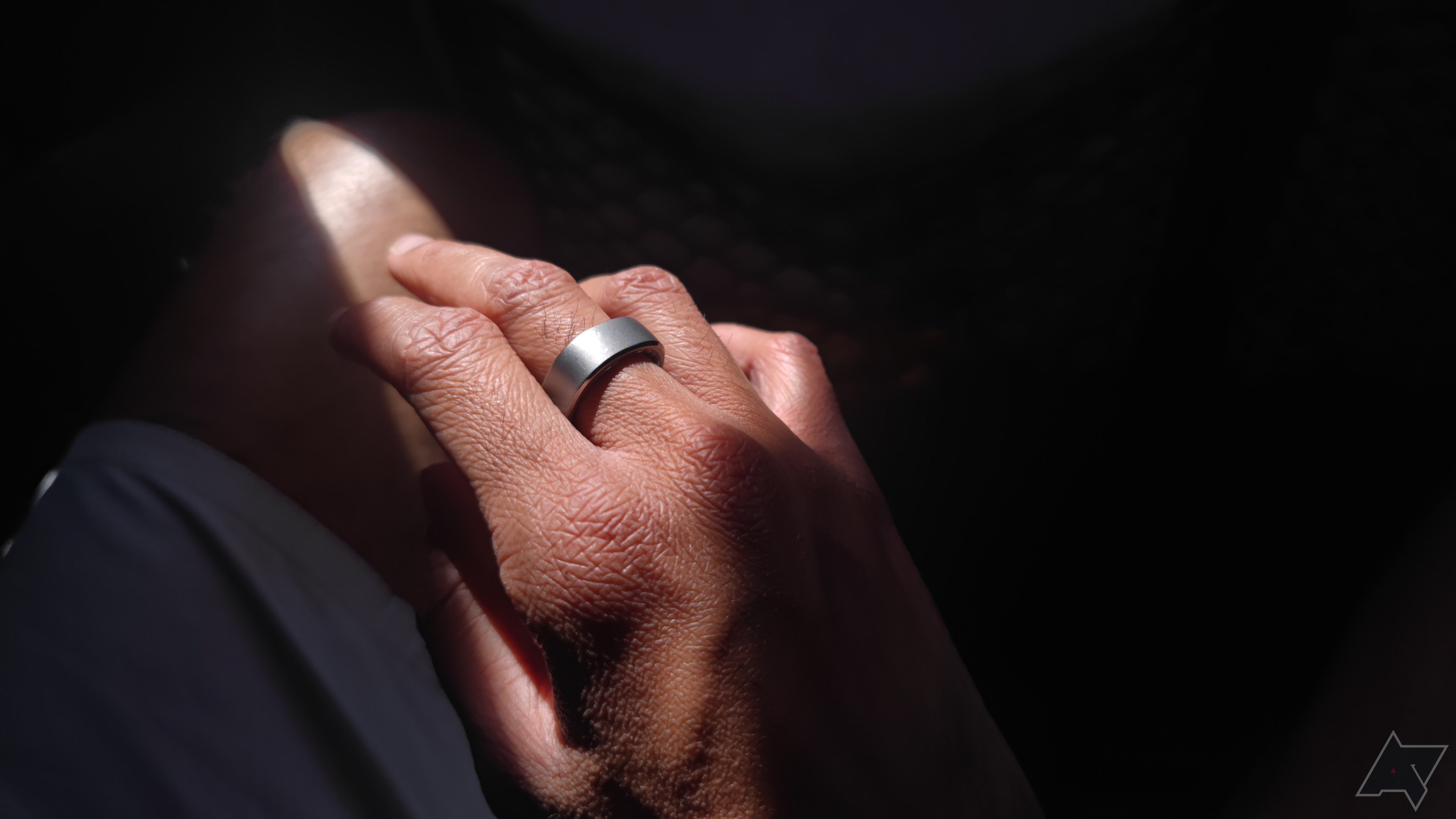 Uma mão usando um anel de prata em iluminação dramática
