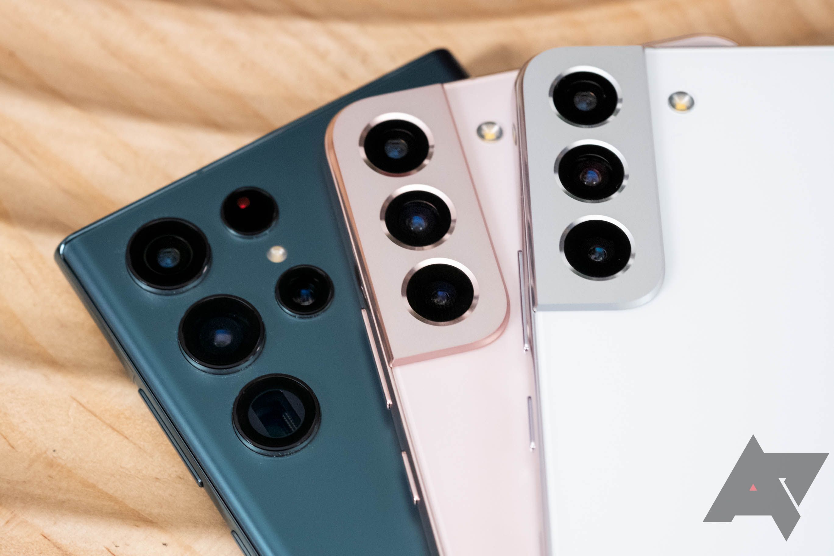 Três smartphones Samsung Galaxy, o S22 Ultra em verde, o S22 Plus em ouro rosa e o S22 em Phantom White, estão empilhados uns sobre os outros.