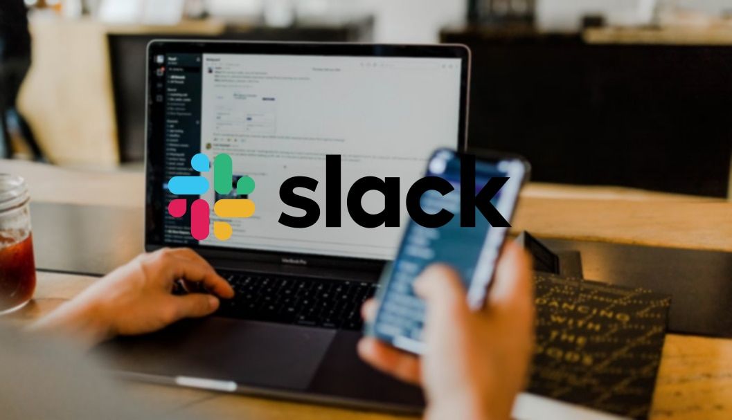 O logotipo do Slack na frente da imagem de uma pessoa usando um telefone e um laptop.