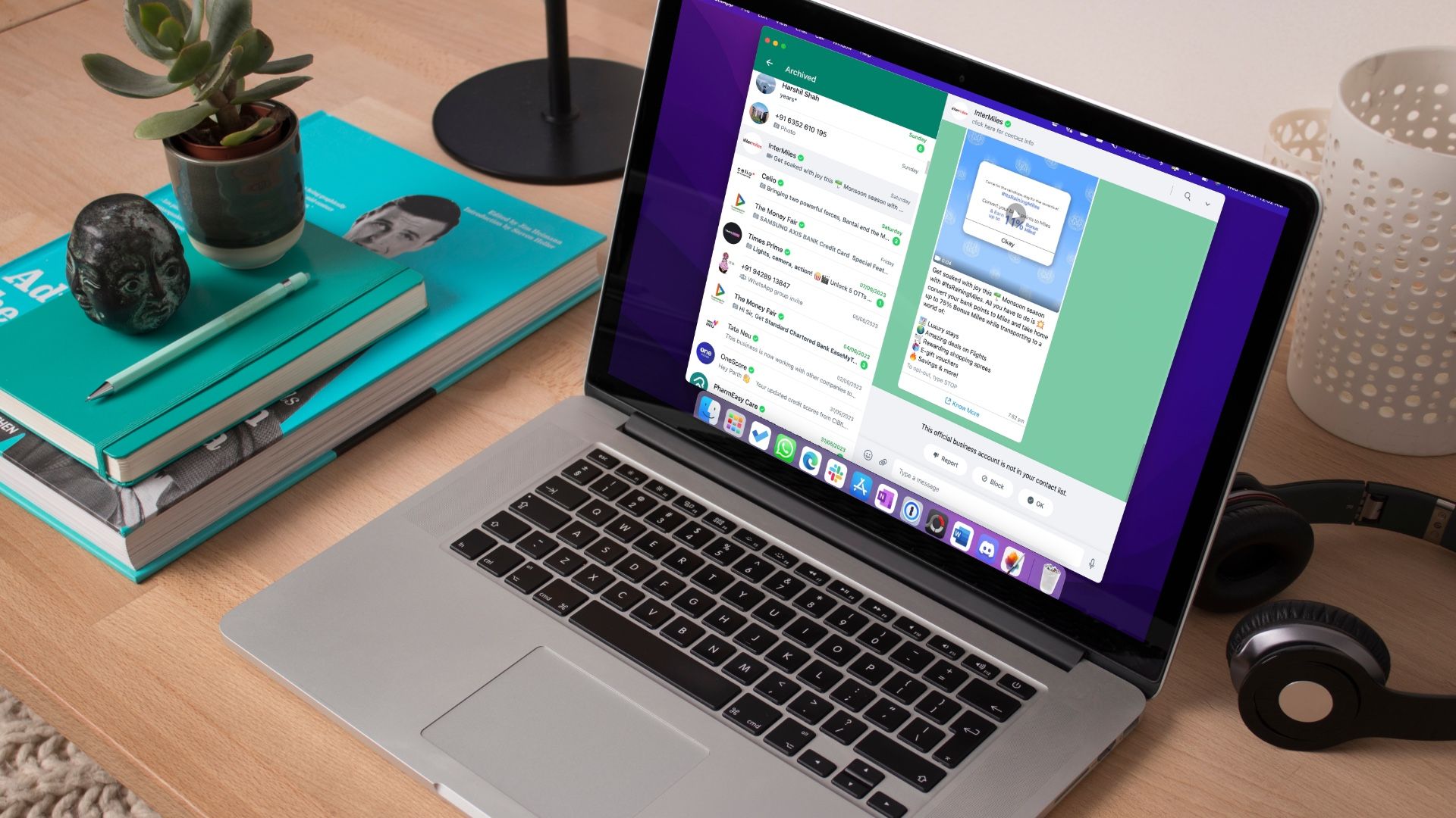 Um MacbookPro com WhatsApp para site em uma mesa de madeira com fones de ouvido e outro objeto próximo