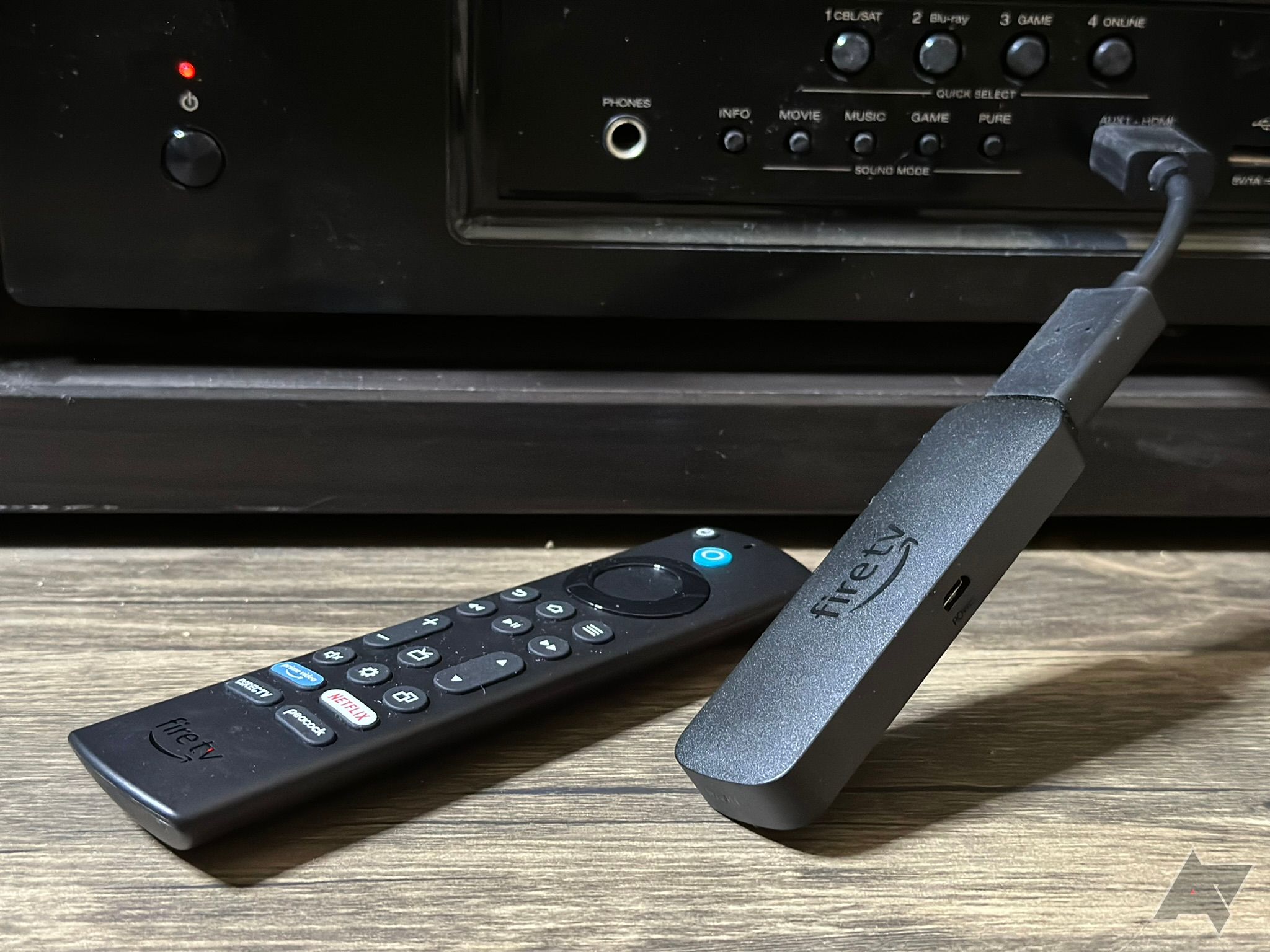 O Fire TV Stick 4K Max e o controle remoto, na frente de um receptor