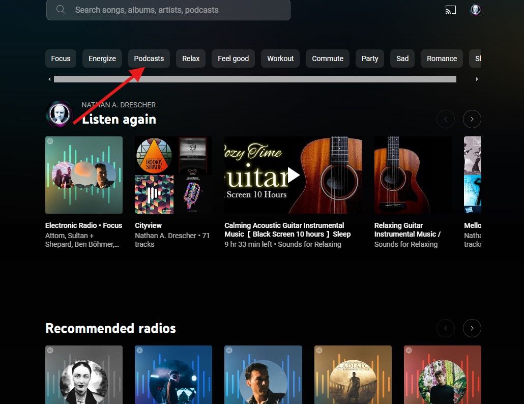 Uma captura de tela da página inicial do YouTube Music com uma seta vermelha apontando para uma pequena caixa onde se lê Podcasts.