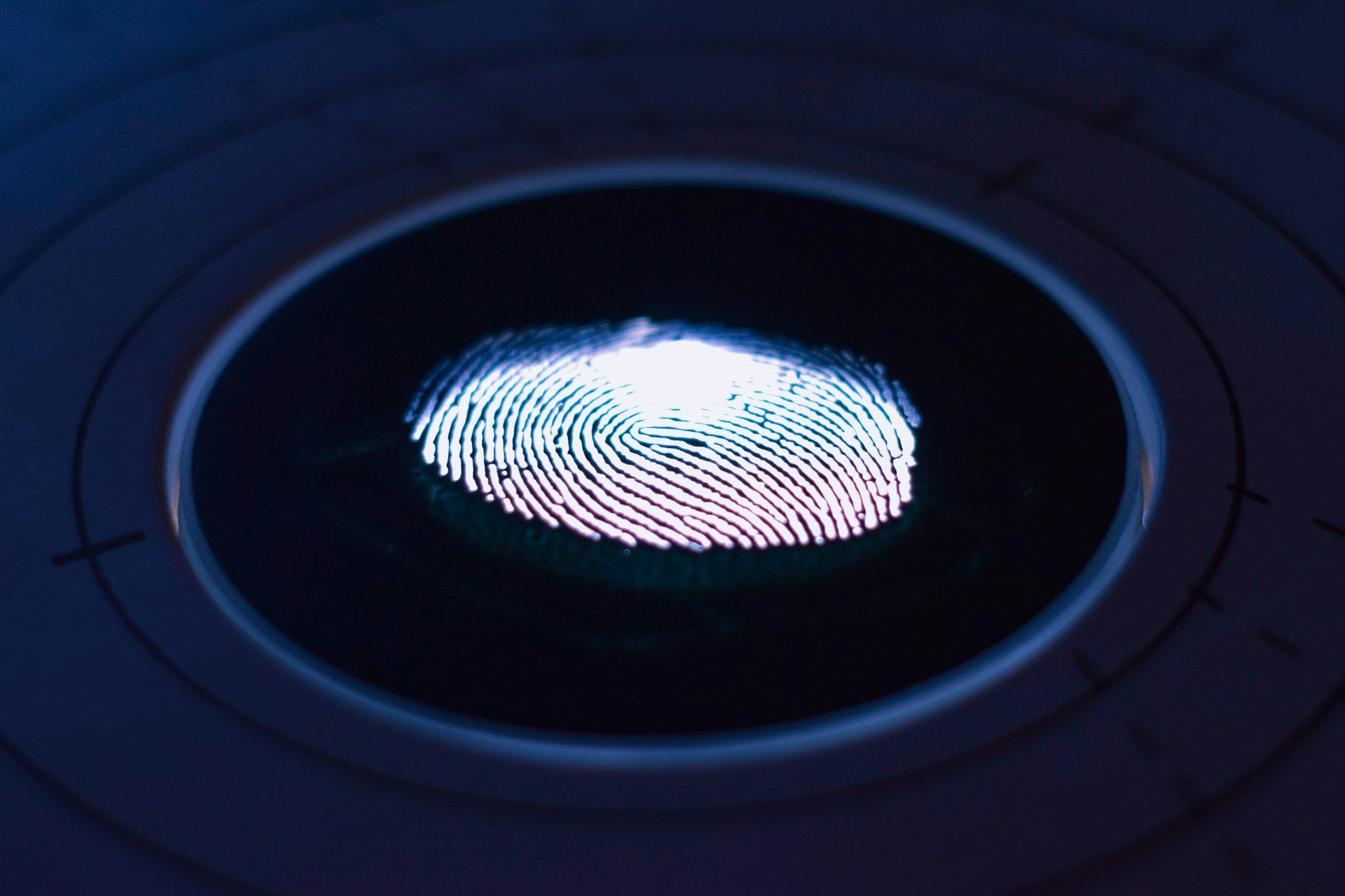   Um padrão de impressão digital brilhante iluminado em um sensor biométrico com círculos concêntricos e marcas de calibração ao redor.