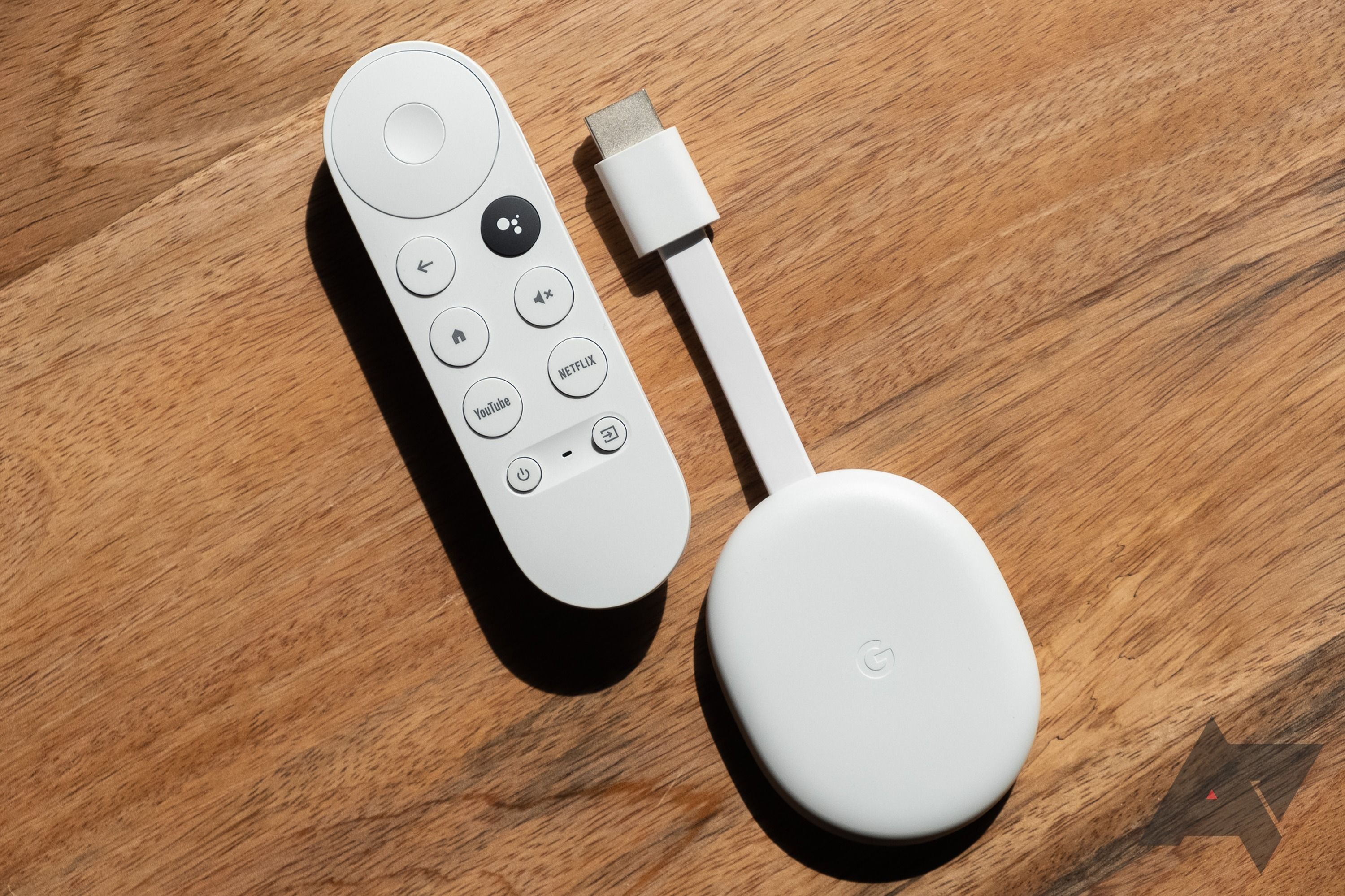 Chromecast com controle remoto do Google TV e dispositivo de streaming em uma superfície de madeira